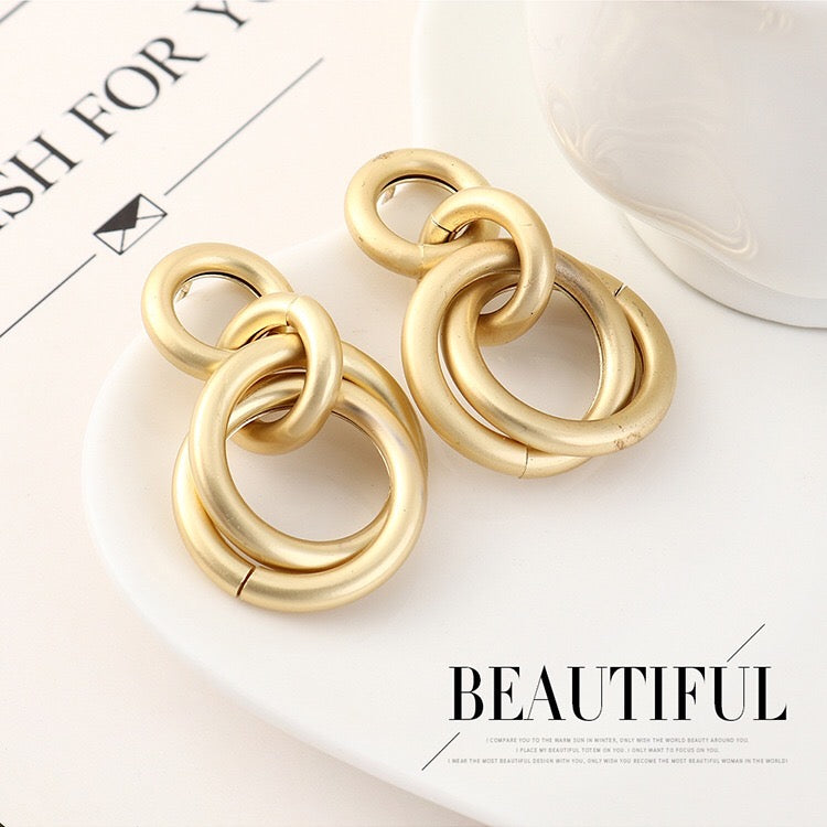 A pair of elegant linking crossed hoops earrings made from brass and s925 silver, showcasing a modern design.