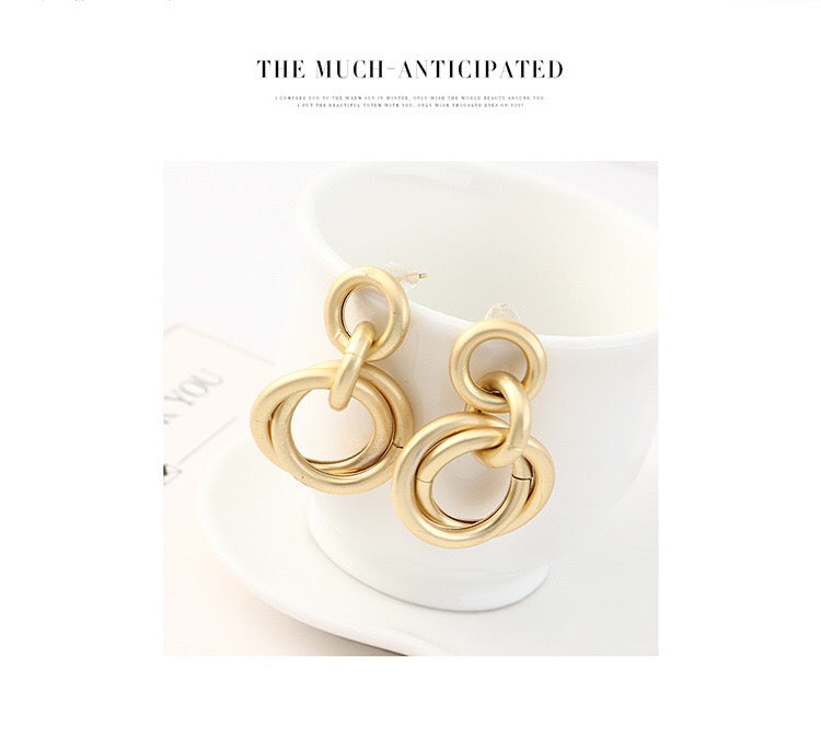 A pair of elegant linking crossed hoops earrings made from brass and s925 silver, showcasing a modern design.