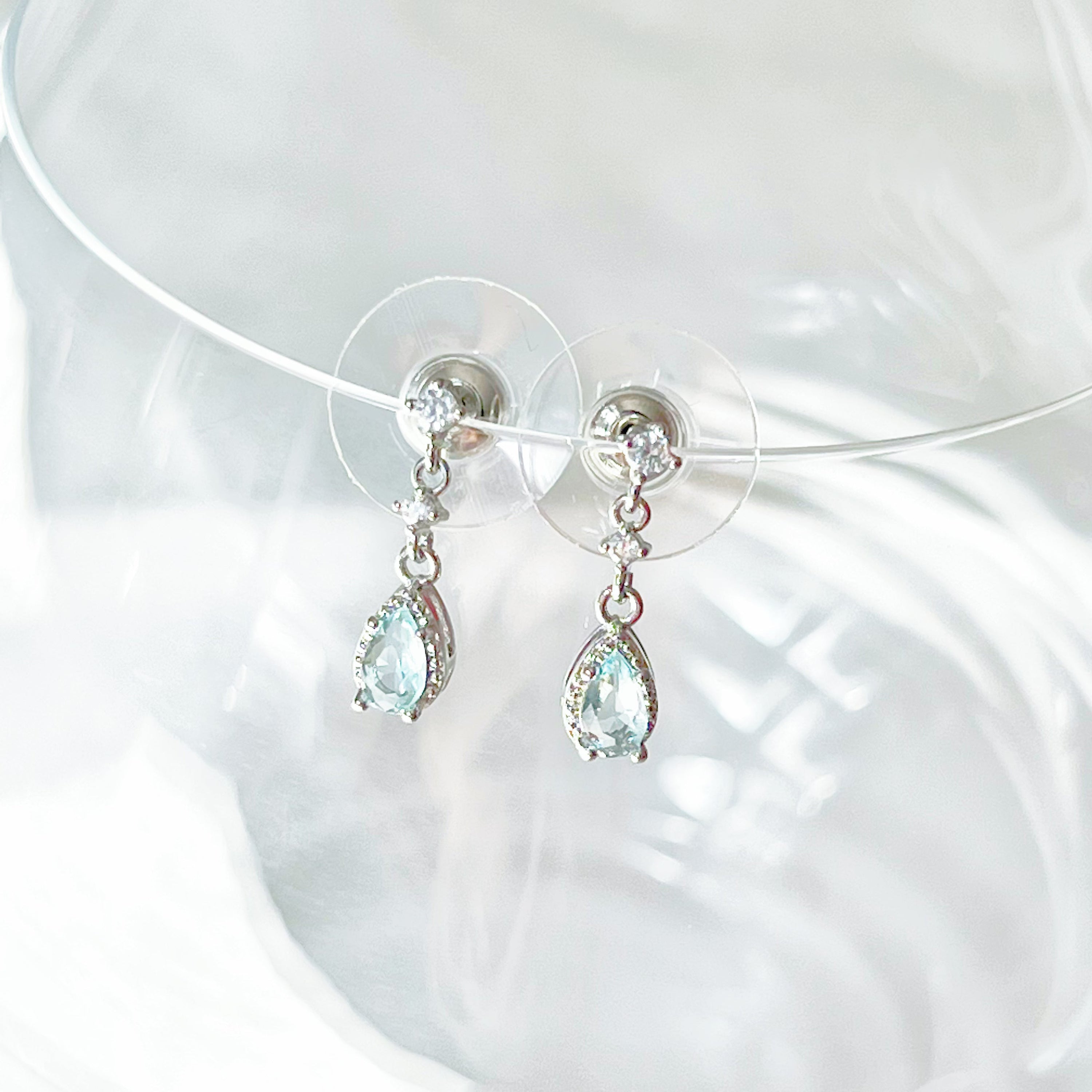 A pair of elegant little blue teardrop crystal earrings made from zircon, featuring a silver-plated bronze body and sterling silver studs.