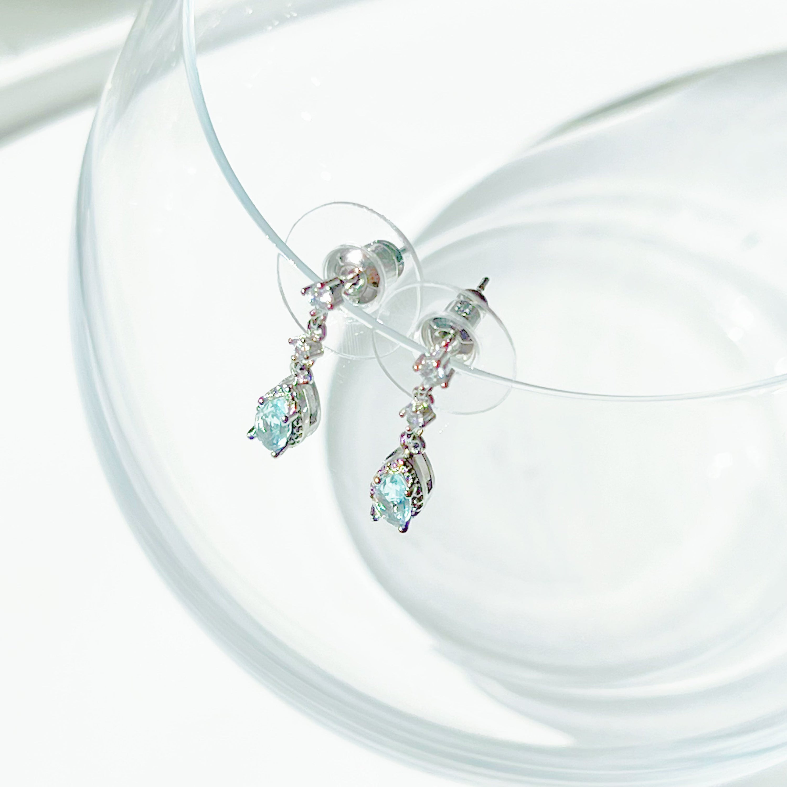 A pair of elegant little blue teardrop crystal earrings made from zircon, featuring a silver-plated bronze body and sterling silver studs.