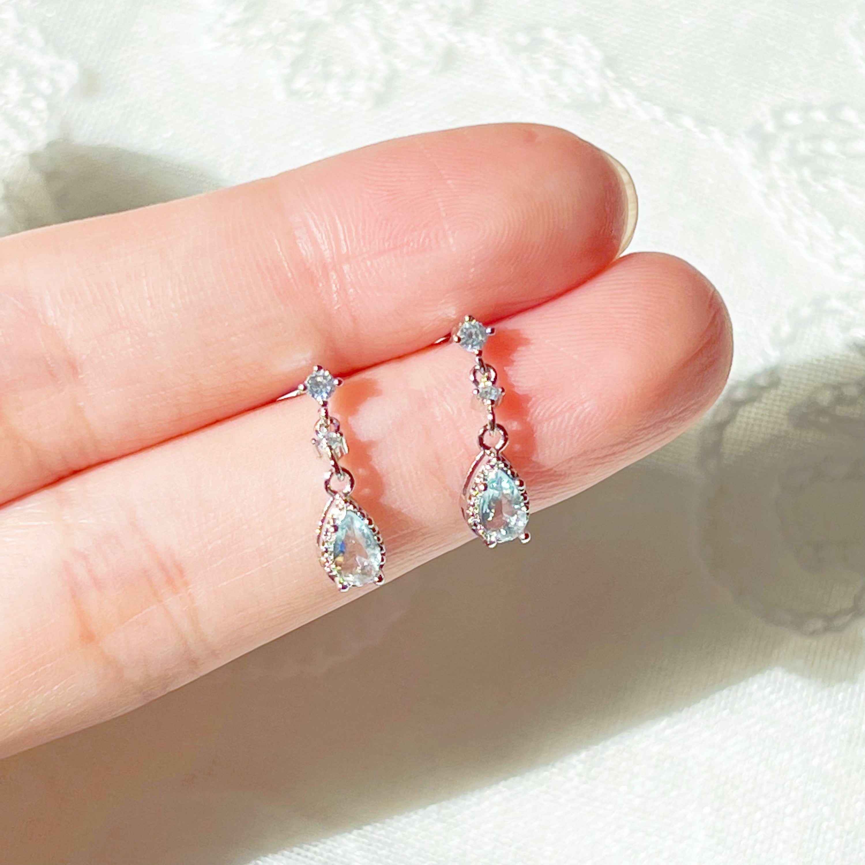 A pair of elegant little blue teardrop crystal earrings made from zircon, featuring a silver-plated bronze body and sterling silver studs.