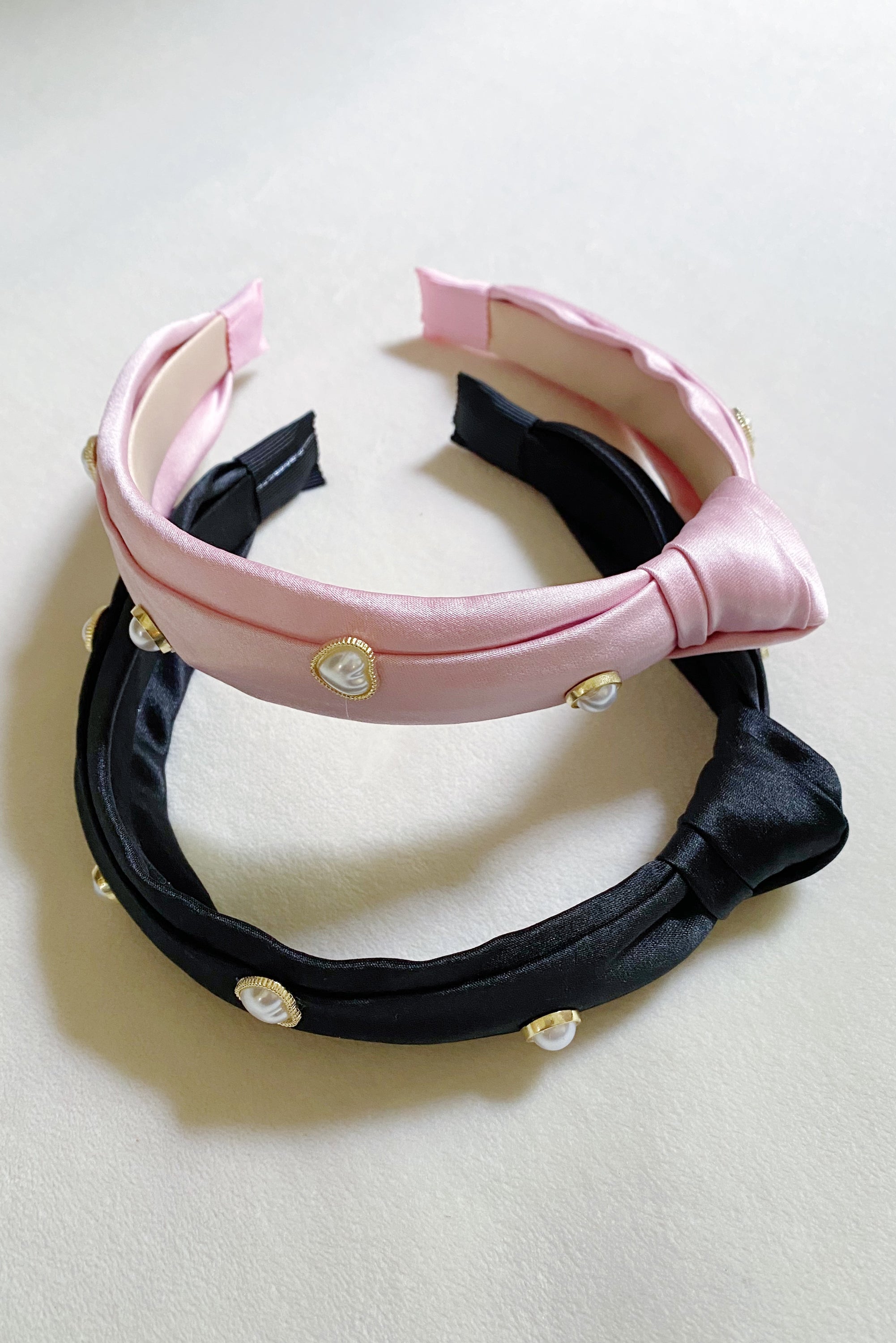 Liz Heart Embellished Headband featuring a chic knotted design and pearl embellishments, made from soft silky material.