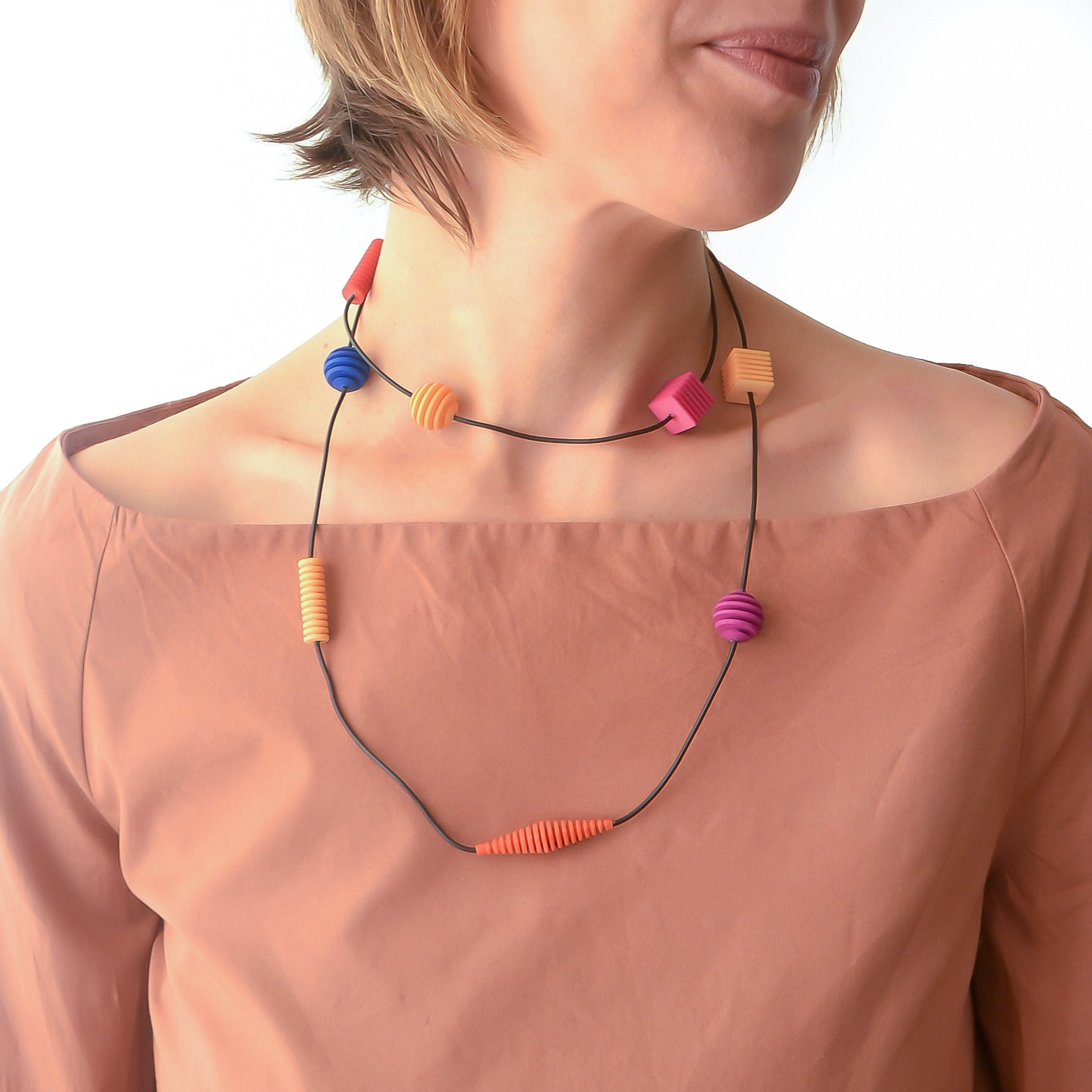 Long Beaded Optical Necklace featuring vibrant hand-dyed beads in geometric shapes, perfect for stylish outfits.