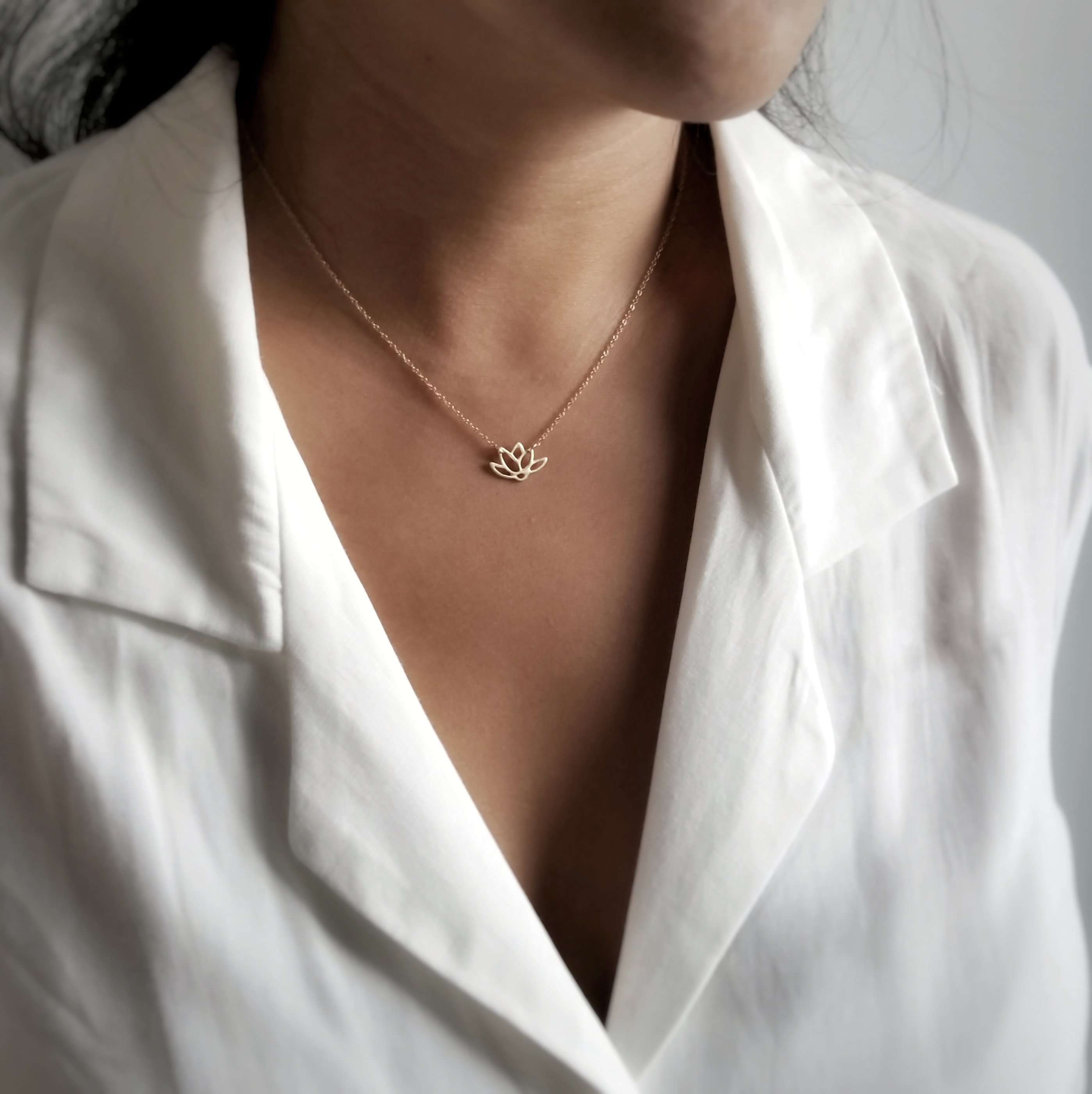 A delicate Lotus Necklace featuring a lotus flower pendant on a 14KT gold-filled or 925 sterling silver chain, symbolizing rebirth and resilience.