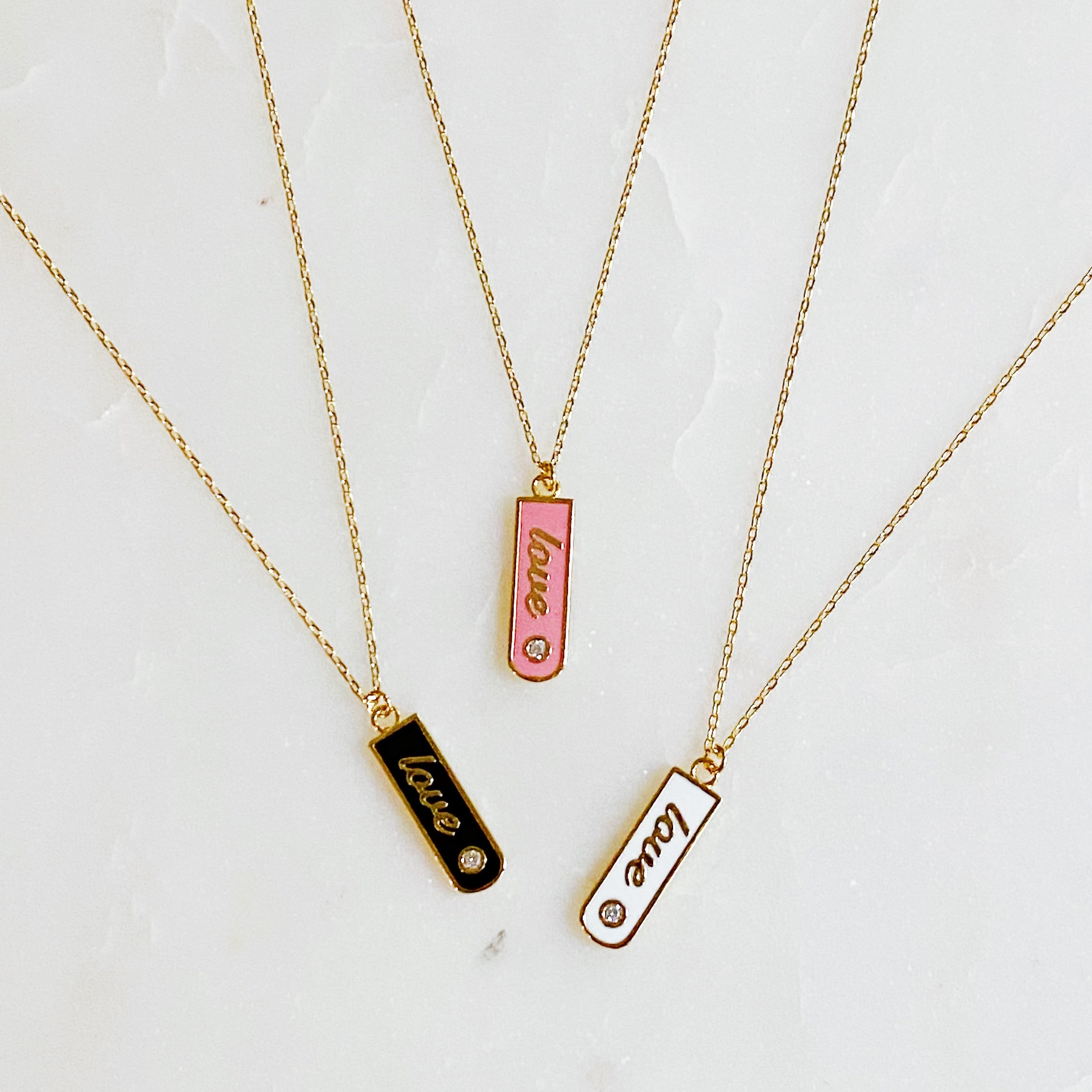 Gold-plated Love Drop Bar Necklace featuring a rounded pendant with LOVE engraving and a tiny shiny stone.