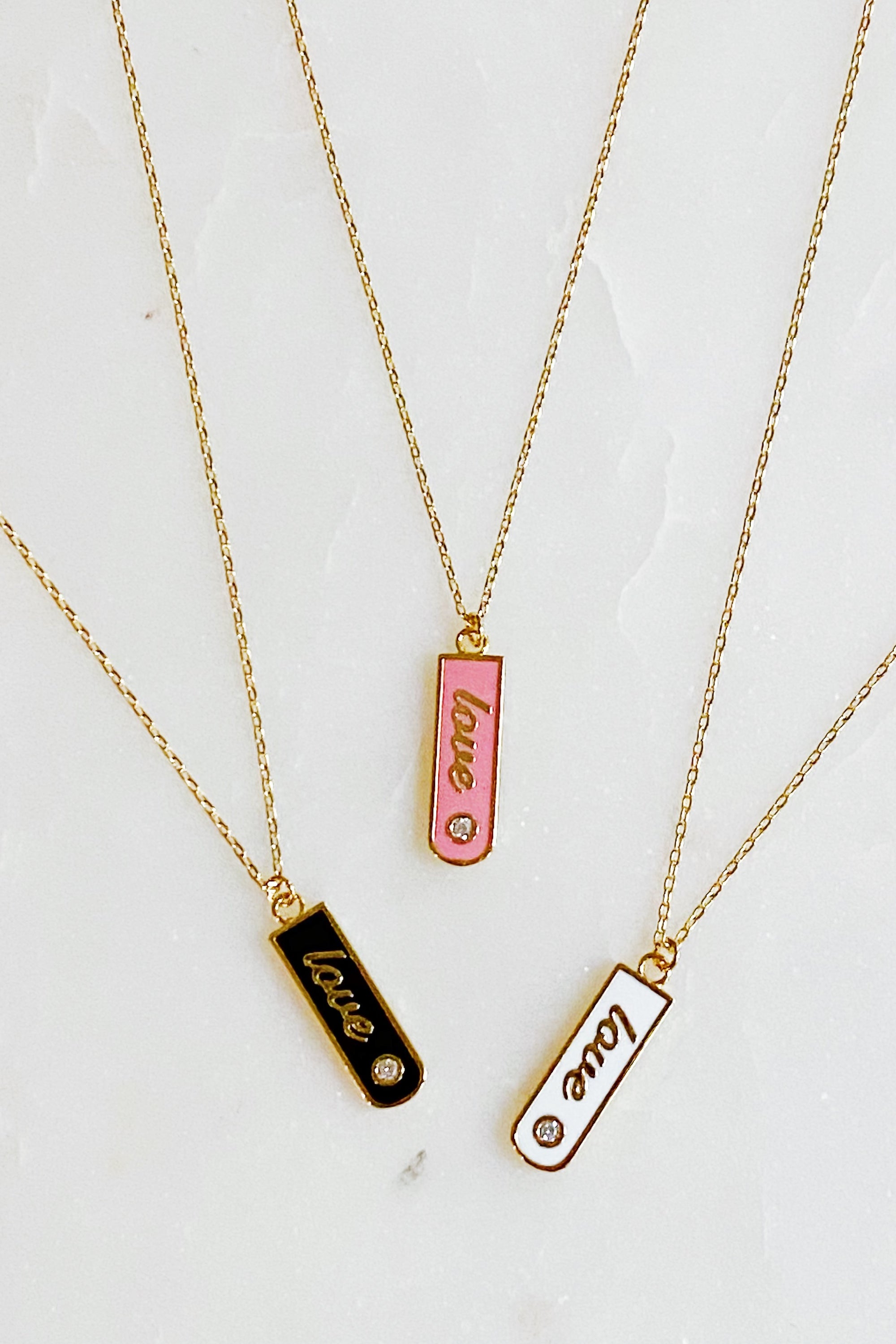 Gold-plated Love Drop Bar Necklace featuring a rounded pendant with LOVE engraving and a tiny shiny stone.