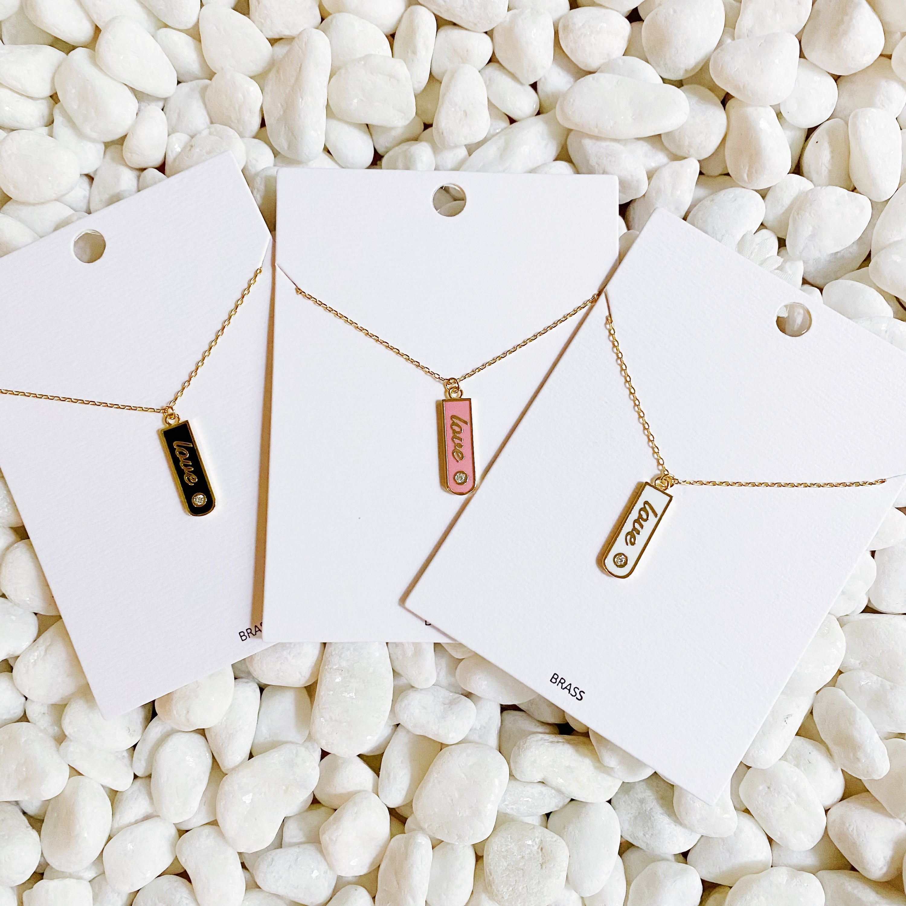 Gold-plated Love Drop Bar Necklace featuring a rounded pendant with LOVE engraving and a tiny shiny stone.