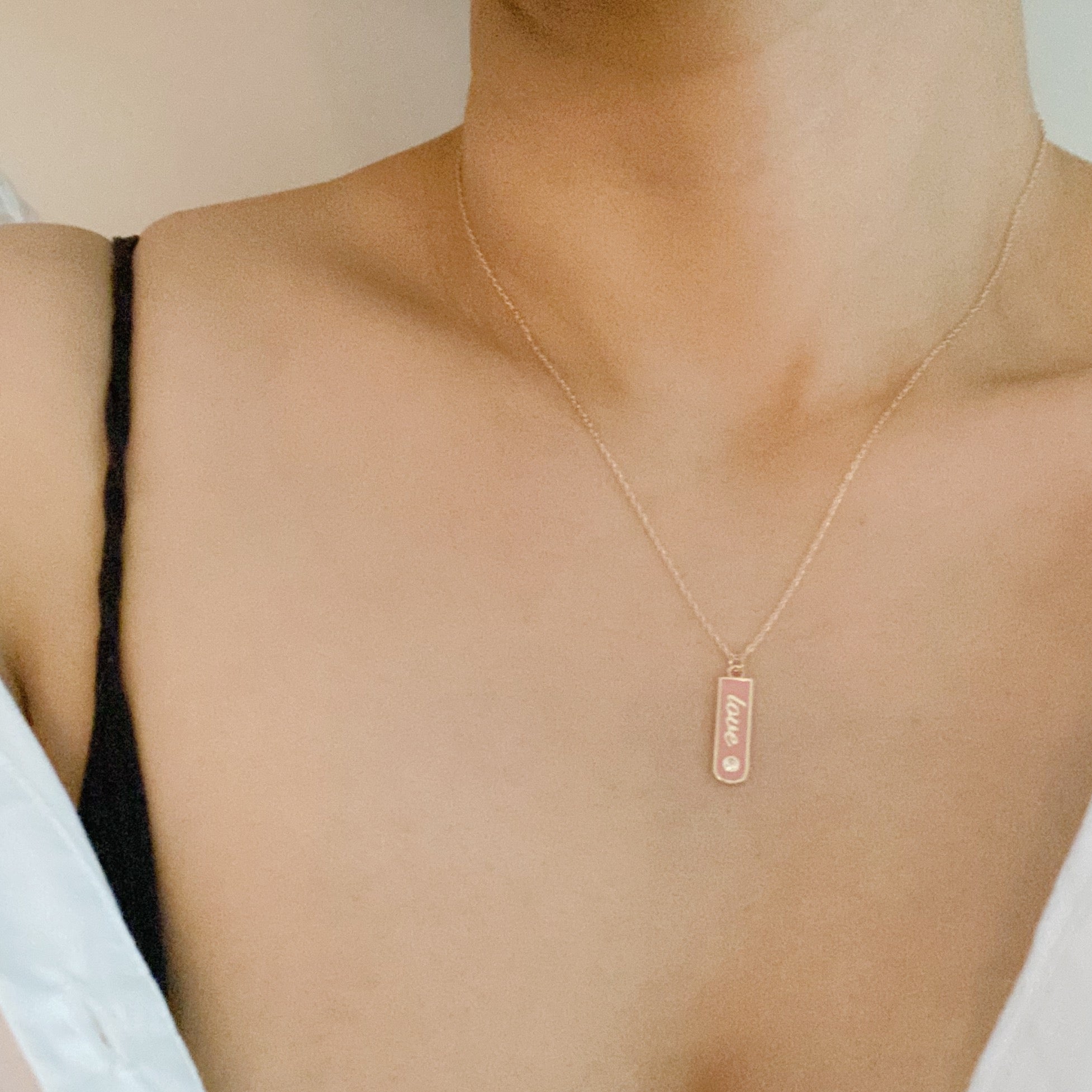 Gold-plated Love Drop Bar Necklace featuring a rounded pendant with LOVE engraving and a tiny shiny stone.