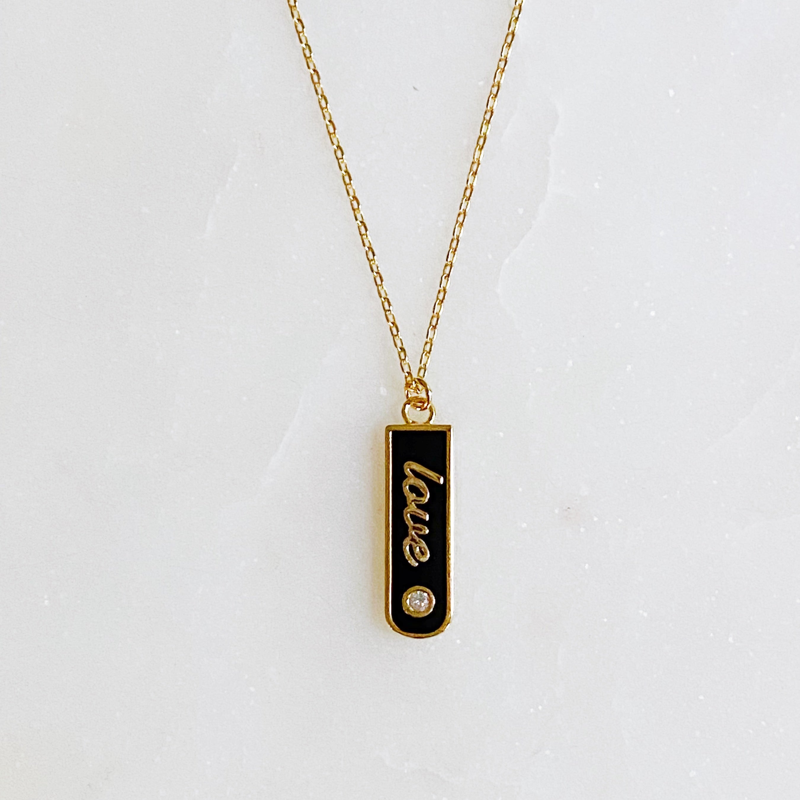 Gold-plated Love Drop Bar Necklace featuring a rounded pendant with LOVE engraving and a tiny shiny stone.