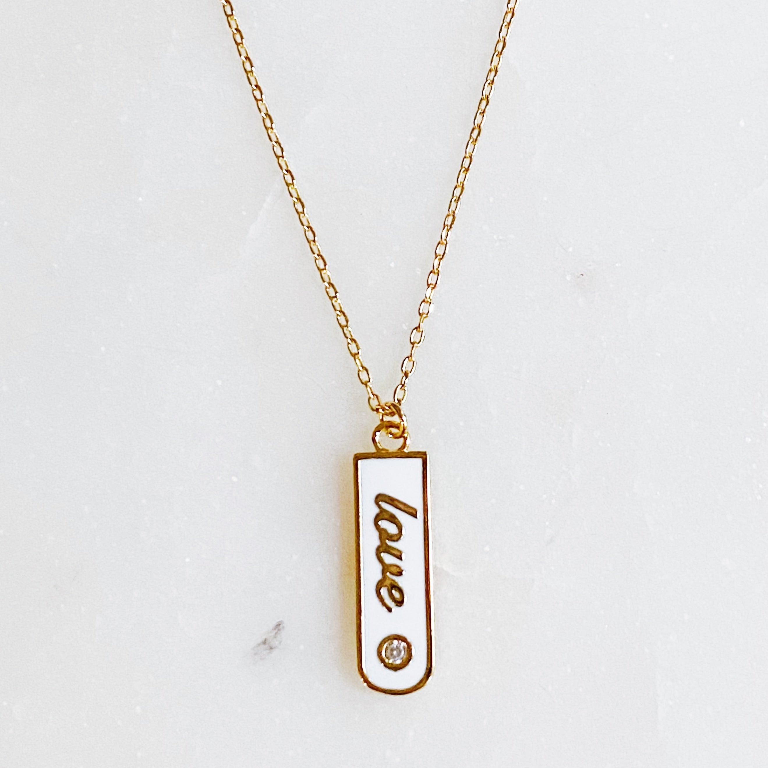 Gold-plated Love Drop Bar Necklace featuring a rounded pendant with LOVE engraving and a tiny shiny stone.