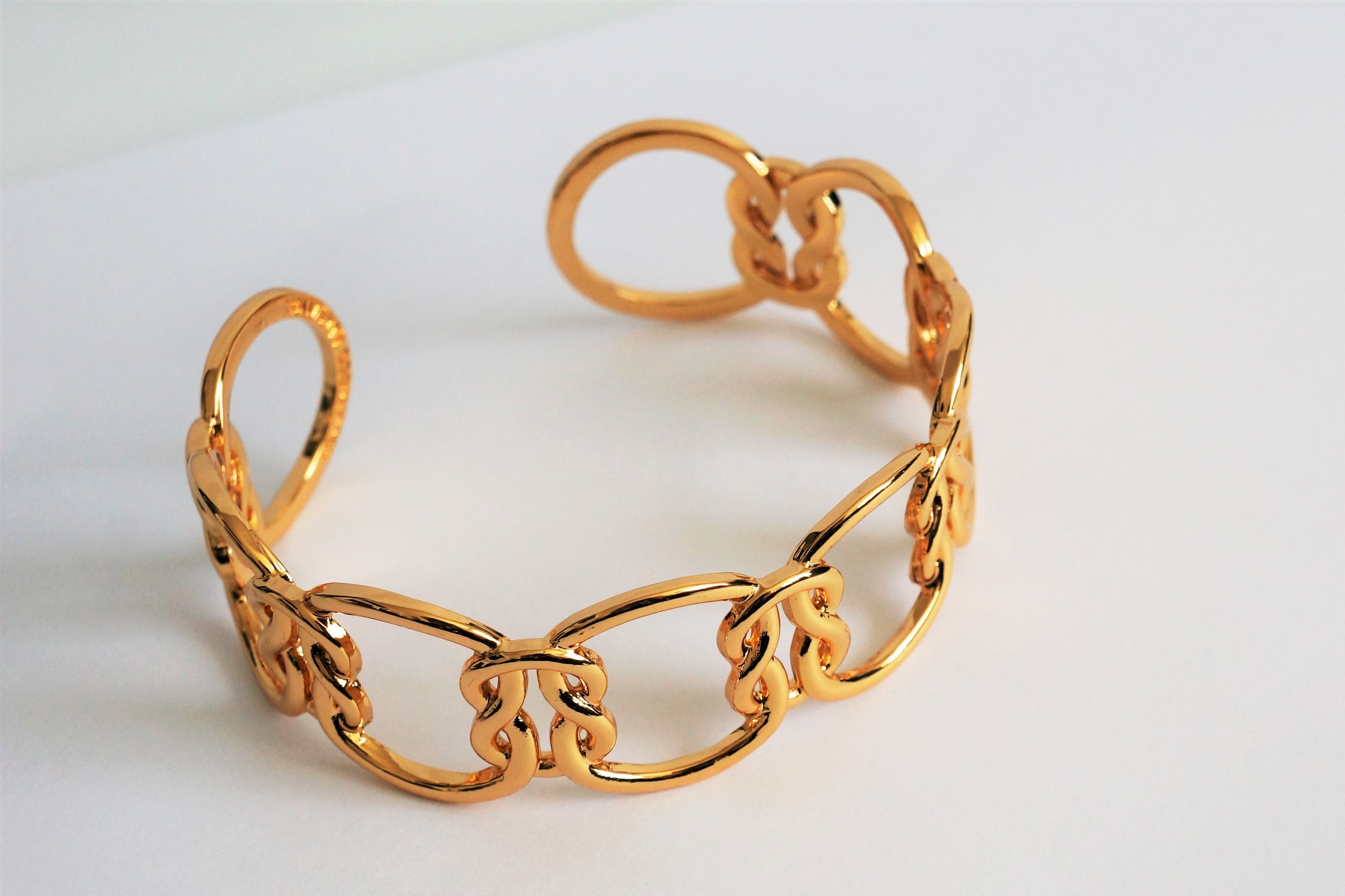 Elegant Love Knot Bracelet in 18k gold plating, symbolizing eternal love, displayed on a soft fabric background.