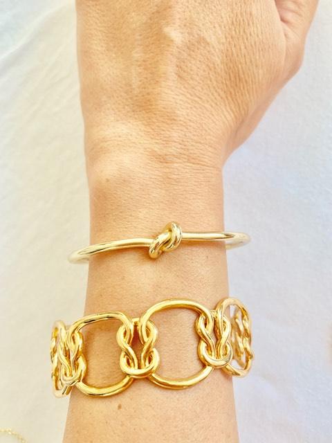 Elegant Love Knot Bracelet in 18k gold plating, symbolizing eternal love, displayed on a soft fabric background.