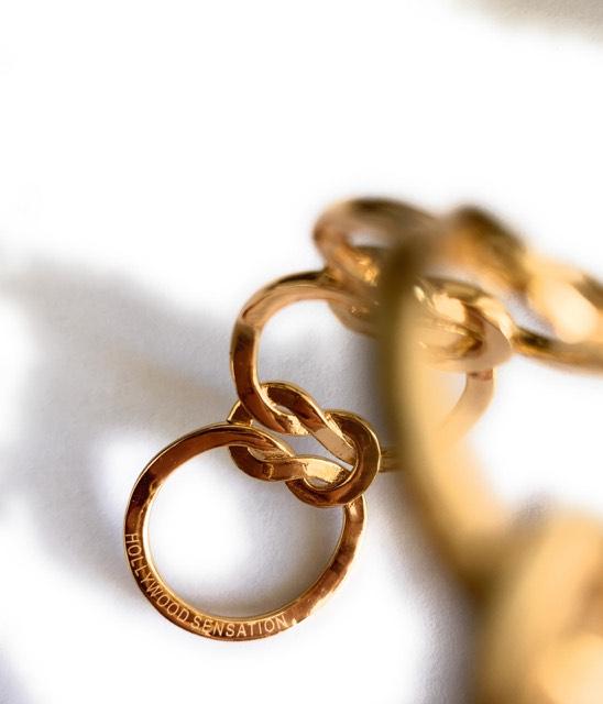 Elegant Love Knot Bracelet in 18k gold plating, symbolizing eternal love, displayed on a soft fabric background.