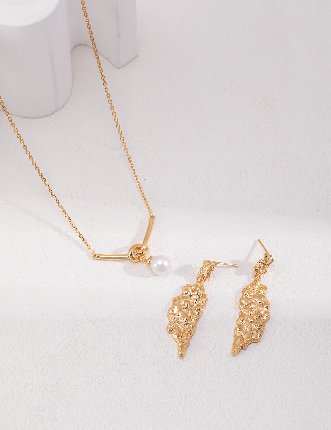 Elegant Love Knot Drop Pearl Necklace featuring natural pearls and gold vermeil, displayed on a soft fabric background.