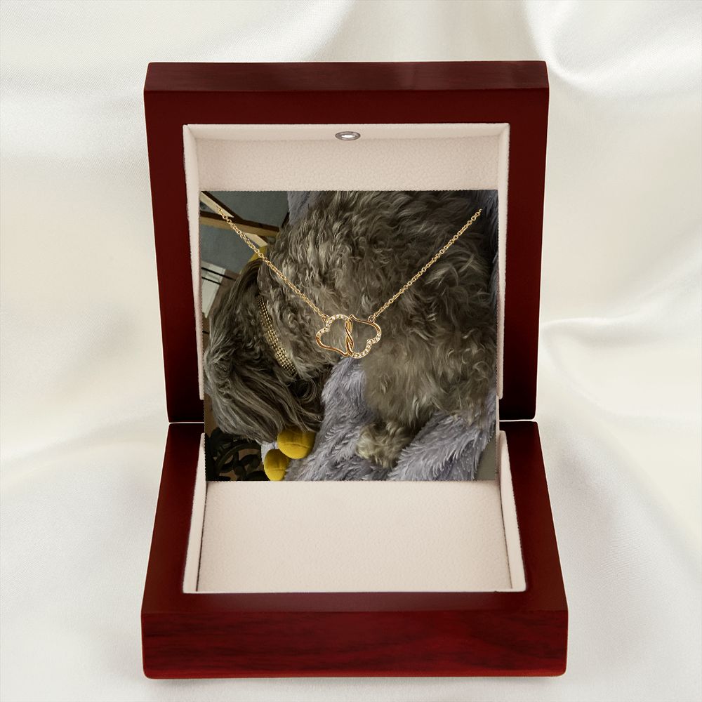 A beautiful 10K solid yellow gold necklace featuring two interconnected hearts adorned with 18 pave set diamonds, presented in a luxurious mahogany gift box.