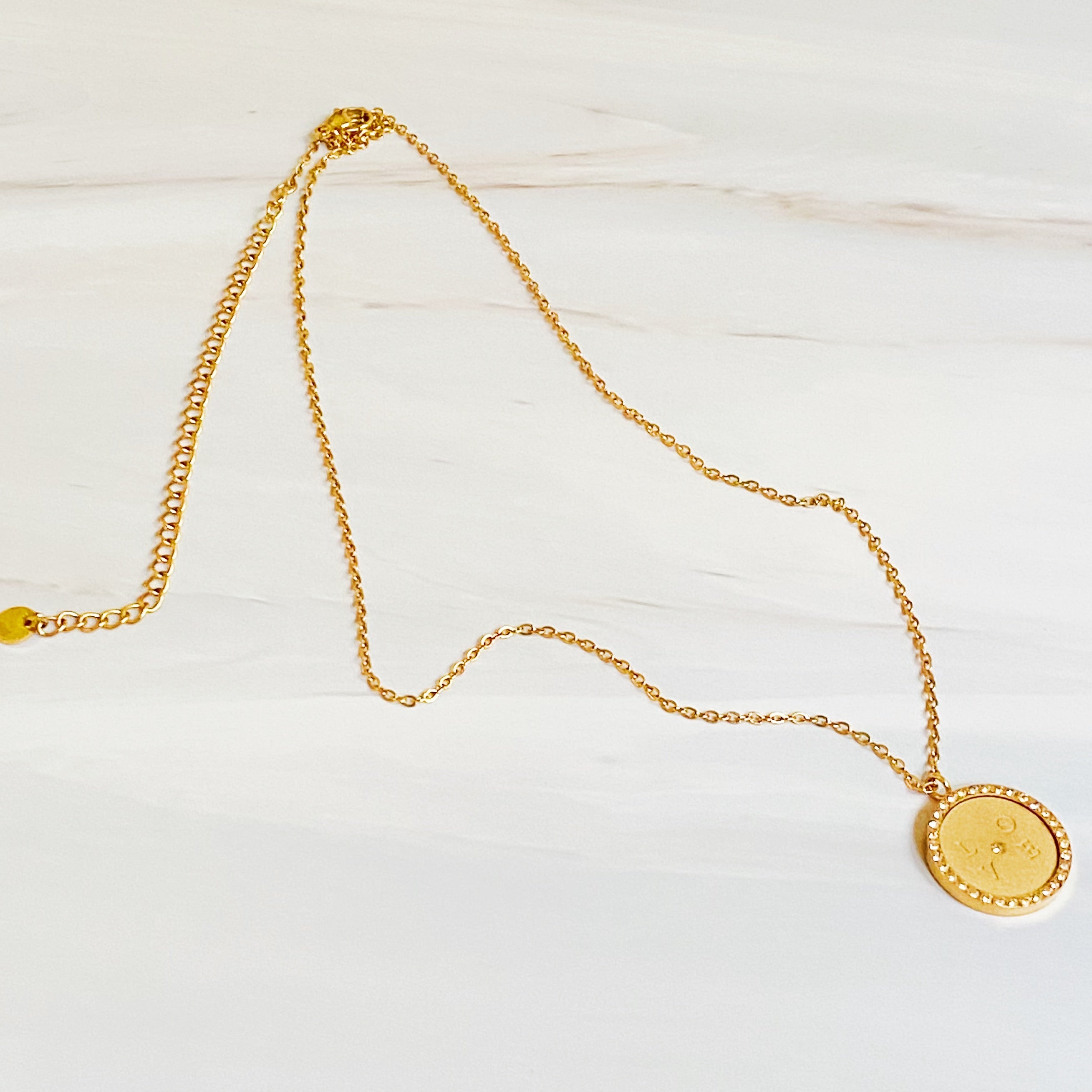 Loveholic Round Pendant Necklace featuring an engraved 'LOVE' design with sparkling cubic zirconia stones on an 18-inch gold plated chain.