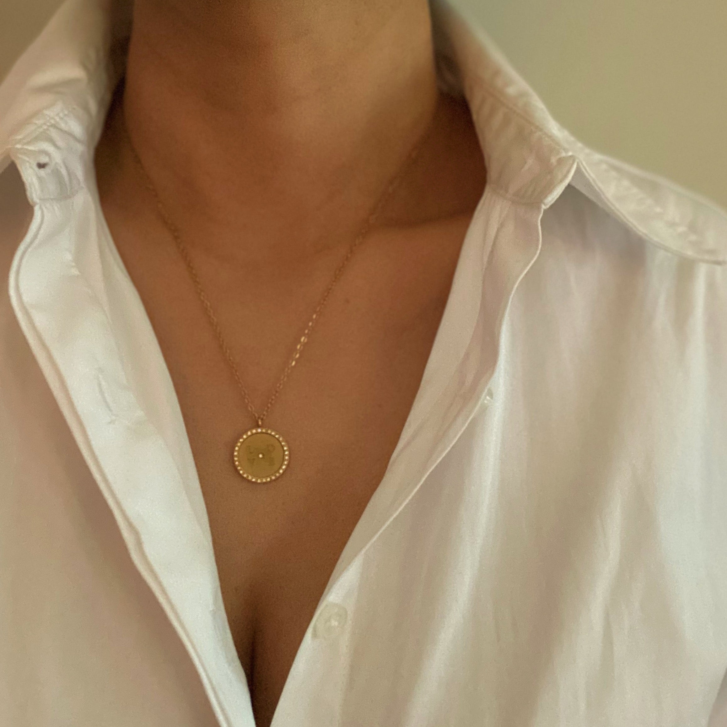 Loveholic Round Pendant Necklace featuring an engraved 'LOVE' design with sparkling cubic zirconia stones on an 18-inch gold plated chain.