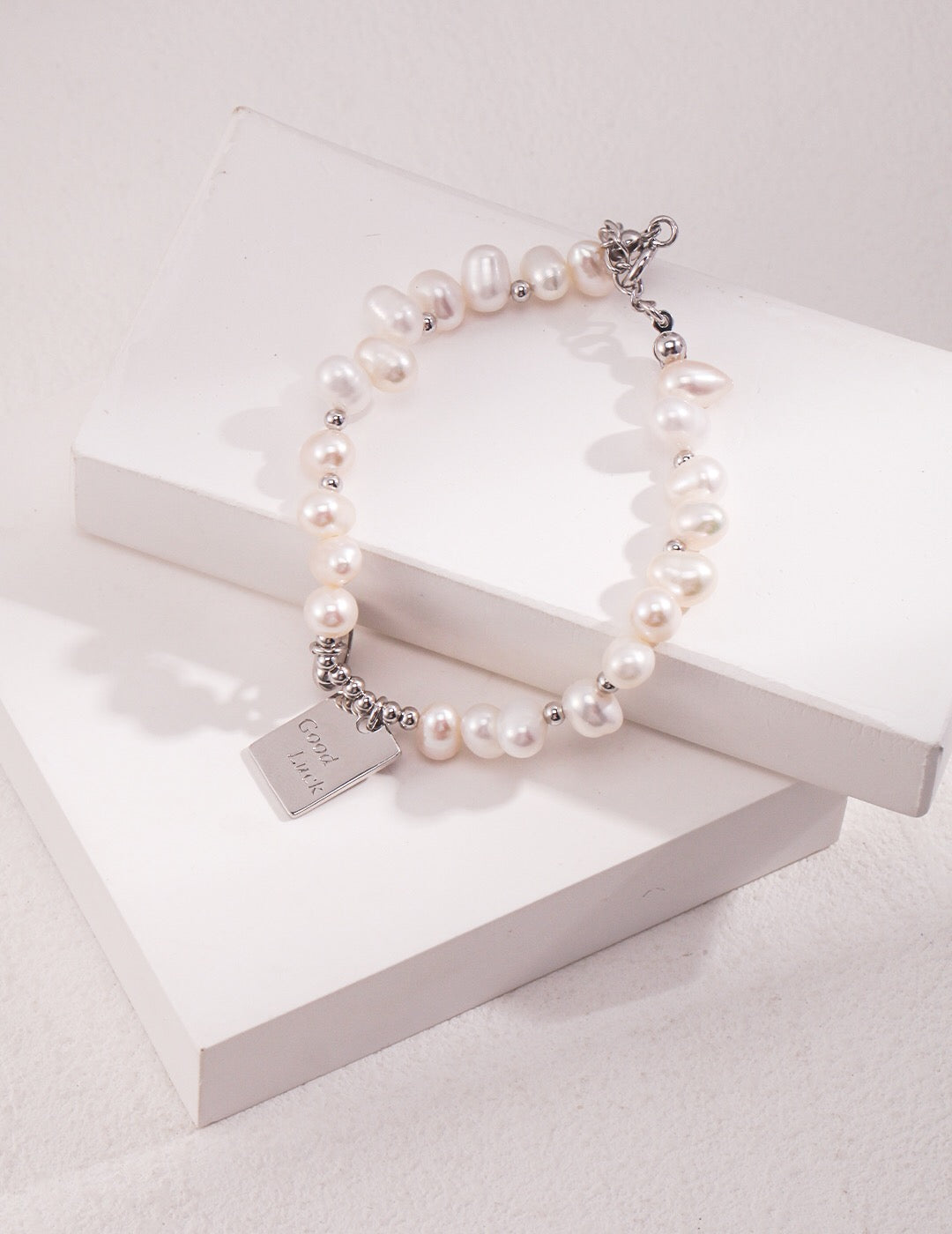 A beautiful Lucky Engraved Freshwater Pearls Bracelet featuring natural pearls, sterling silver, and gold vermeil, elegantly displayed on a soft surface.