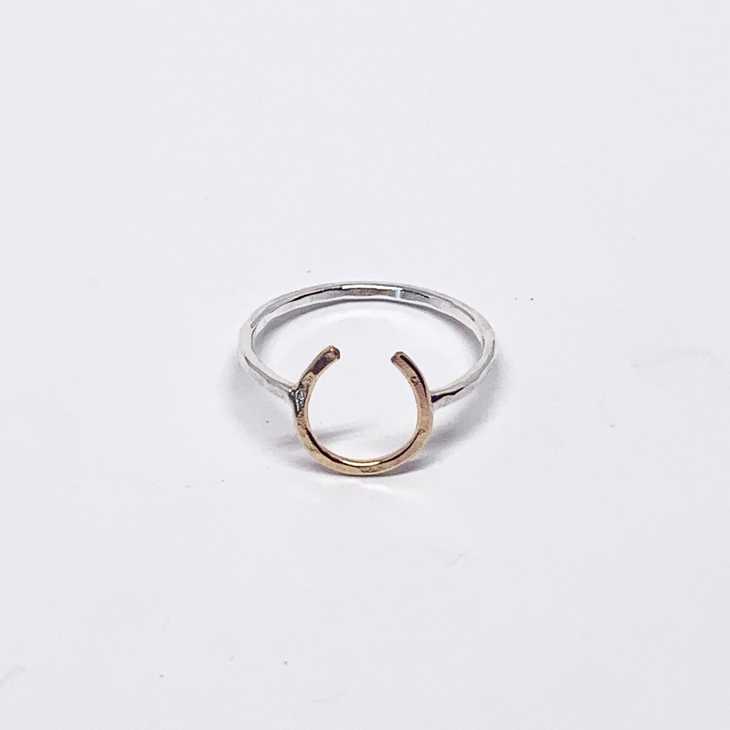 A two-toned Lucky Horseshoe Ring made from hand-formed and hammered wire, symbolizing good luck and western culture.