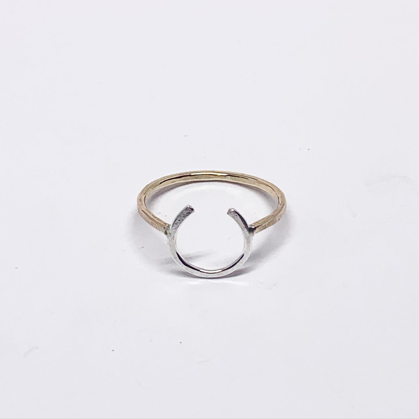 A two-toned Lucky Horseshoe Ring made from hand-formed and hammered wire, symbolizing good luck and western culture.