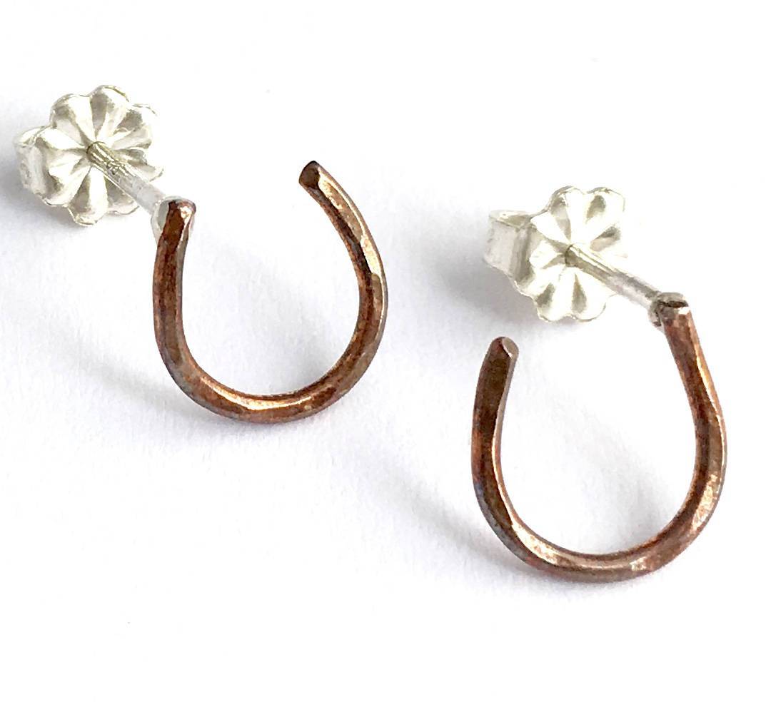 A pair of handmade Lucky Horseshoe Stud Earrings crafted from recycled metals, showcasing a classic western design.