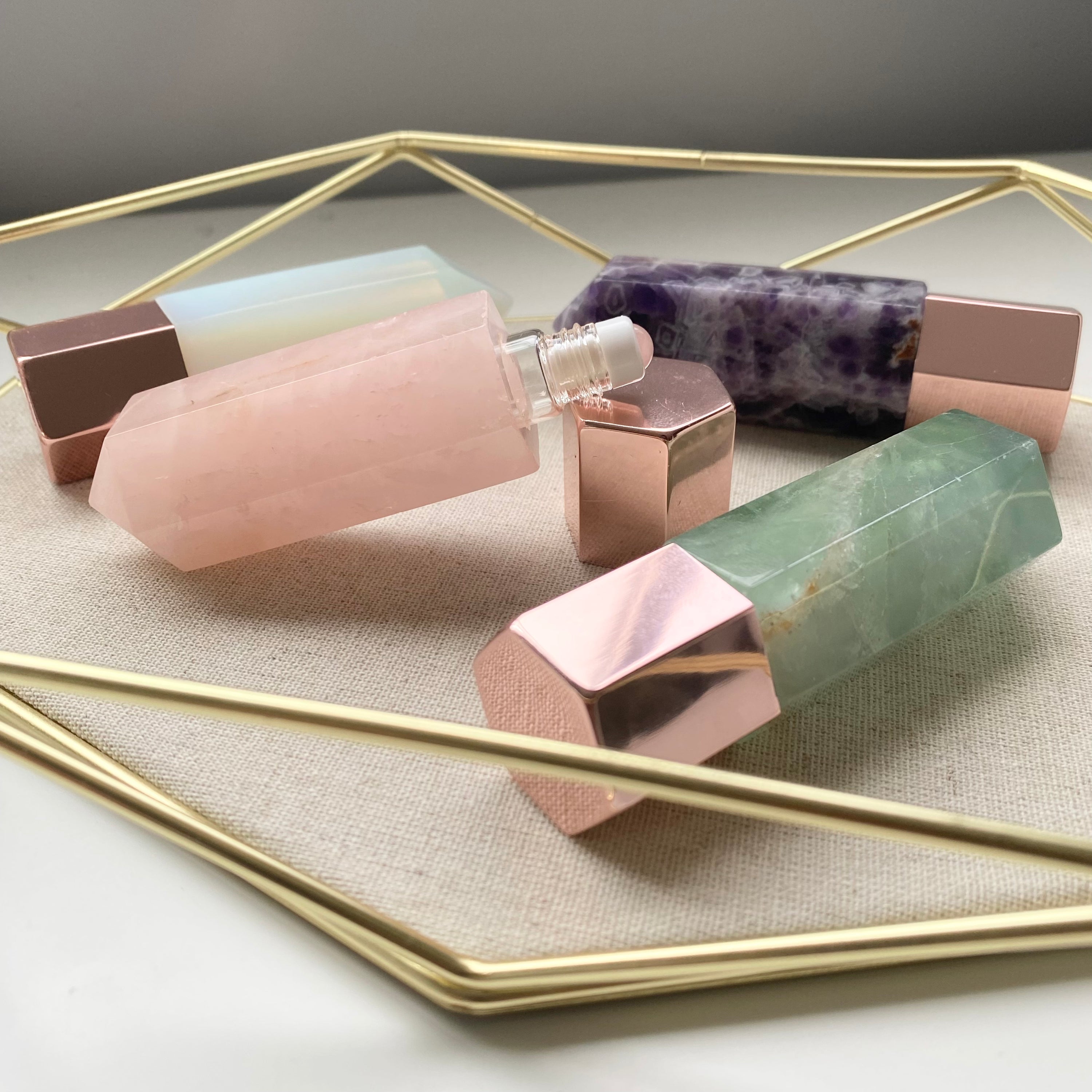 A luxurious gemstone perfume bottle featuring a stunning gemstone point roller design, available in Opalite, Amethyst, Rose Quartz, and Green Fluorite.