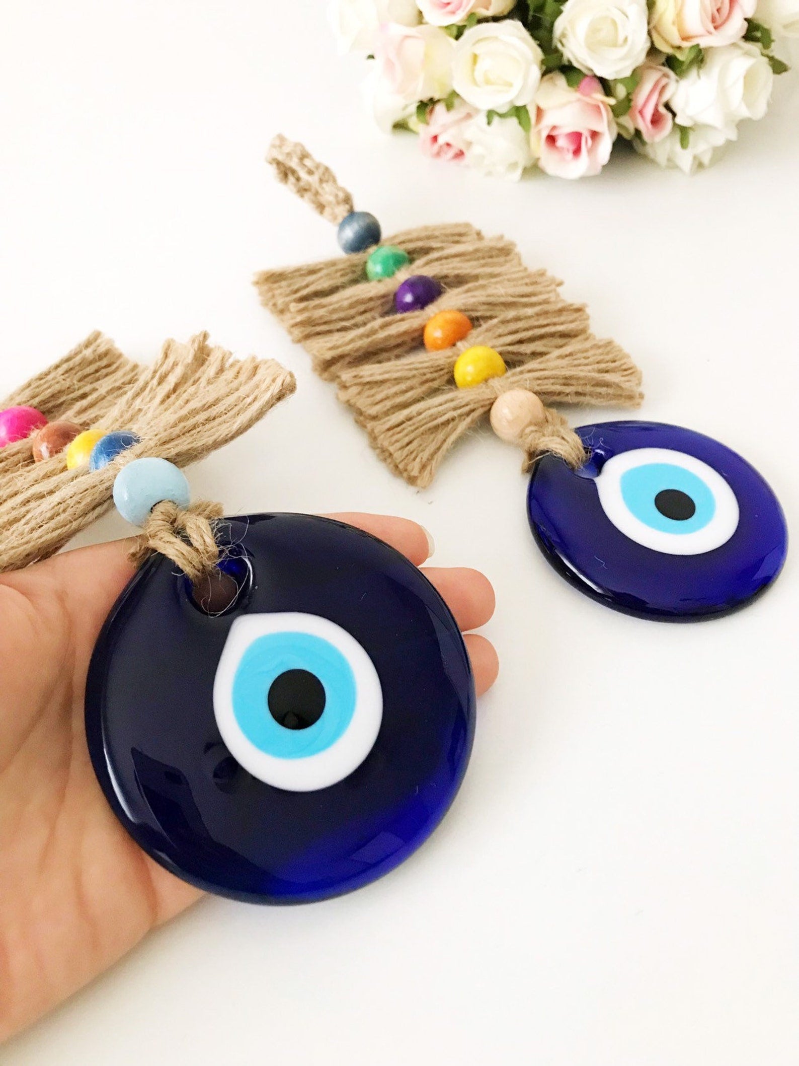 Colorful macrame wall hanging featuring a large evil eye bead and tiny wood beads, perfect for home decor.