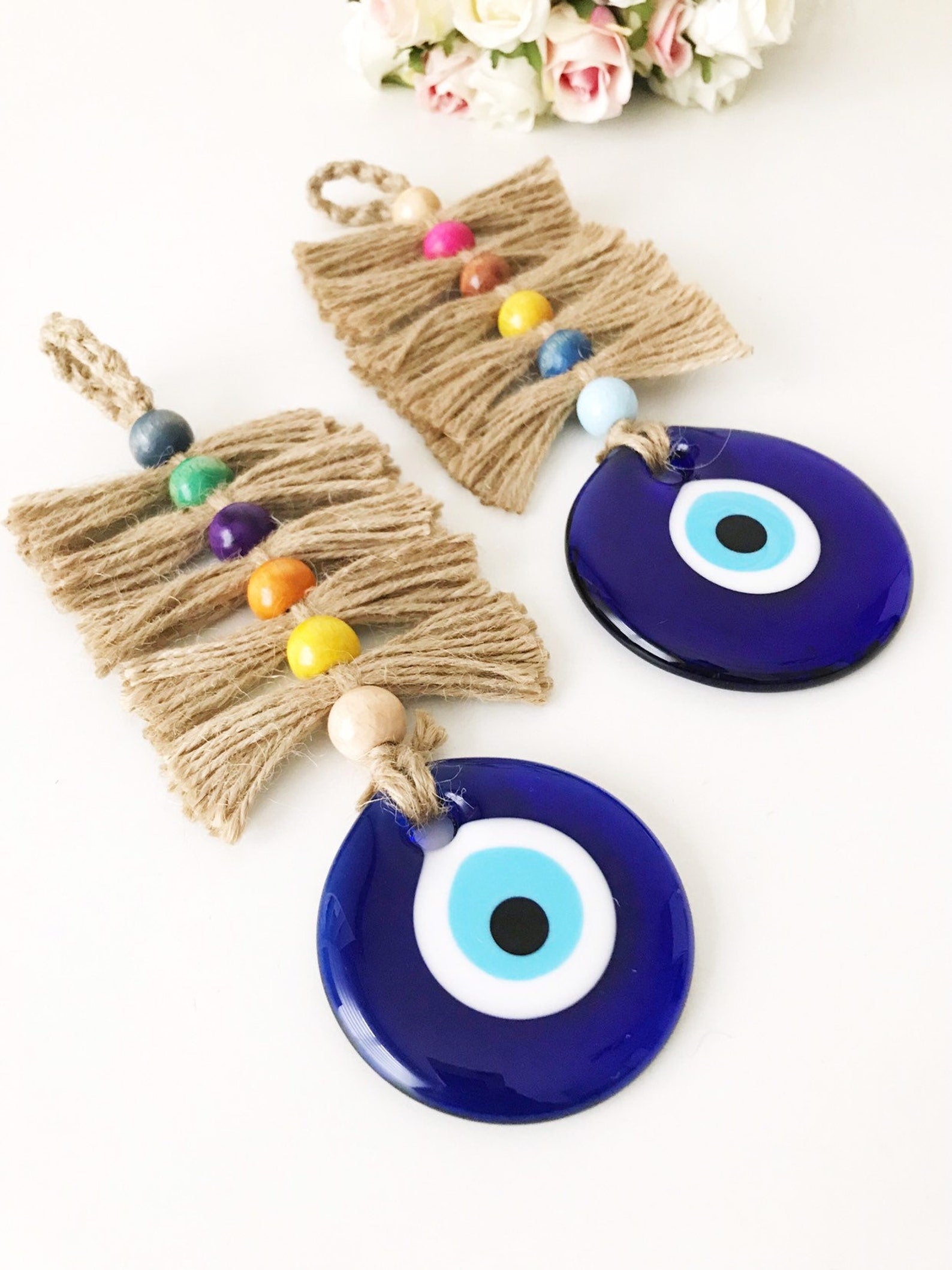 Colorful macrame wall hanging featuring a large evil eye bead and tiny wood beads, perfect for home decor.