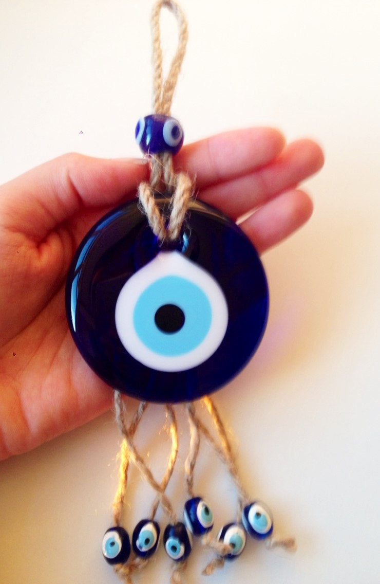 Handmade macrame wall hanging featuring a large blue evil eye and seven smaller evil eyes, symbolizing protection and positivity.