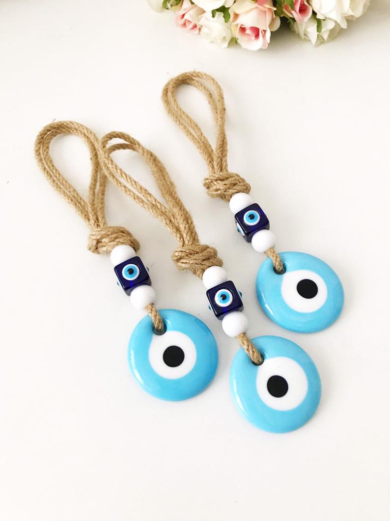 Handmade macrame wall hanging featuring a turquoise glass evil eye bead and blue plastic beads, measuring 21cm in length.