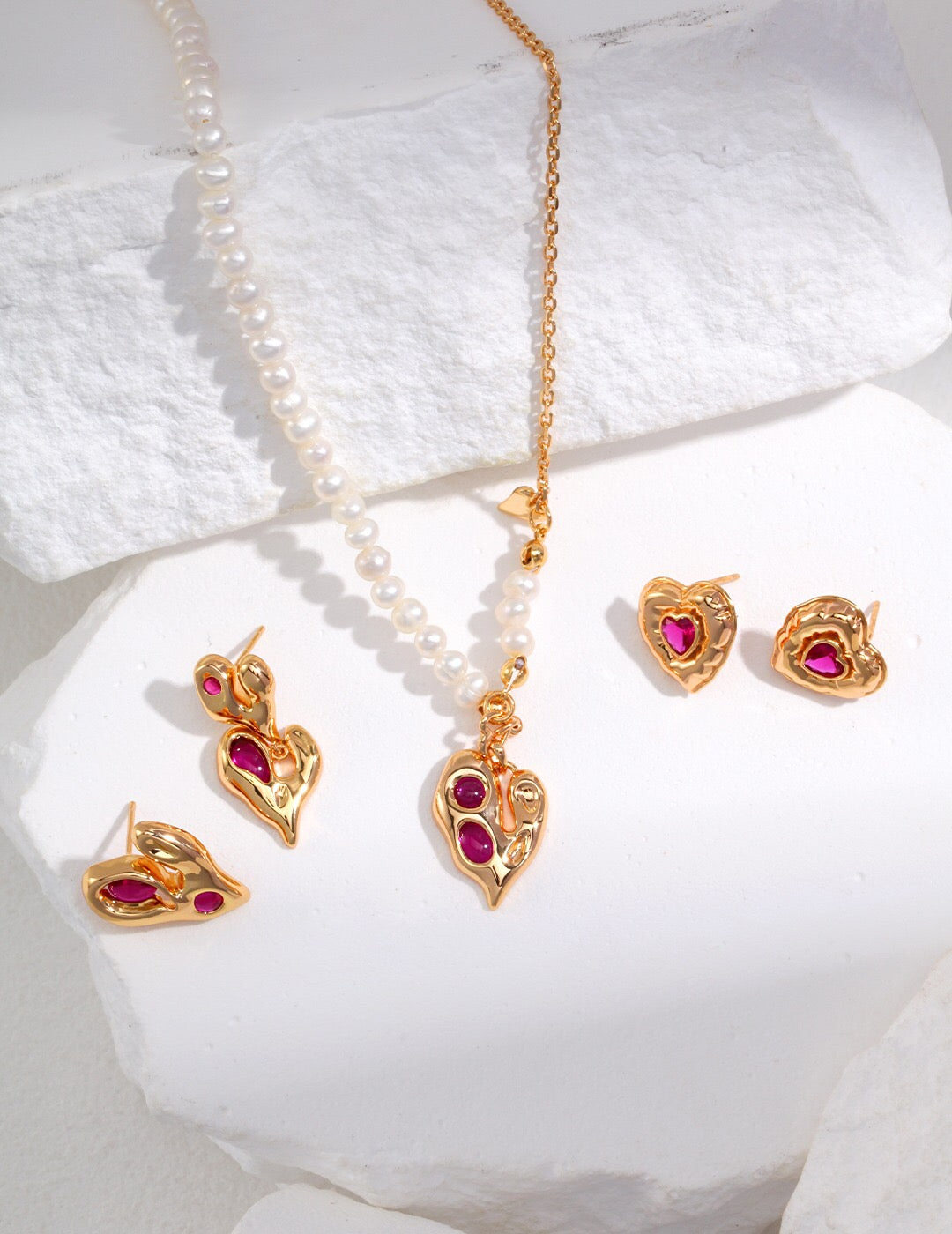 A pair of handmade magenta cubic zirconia irregular heart drop earrings, featuring gold vermeil plating and a unique design.