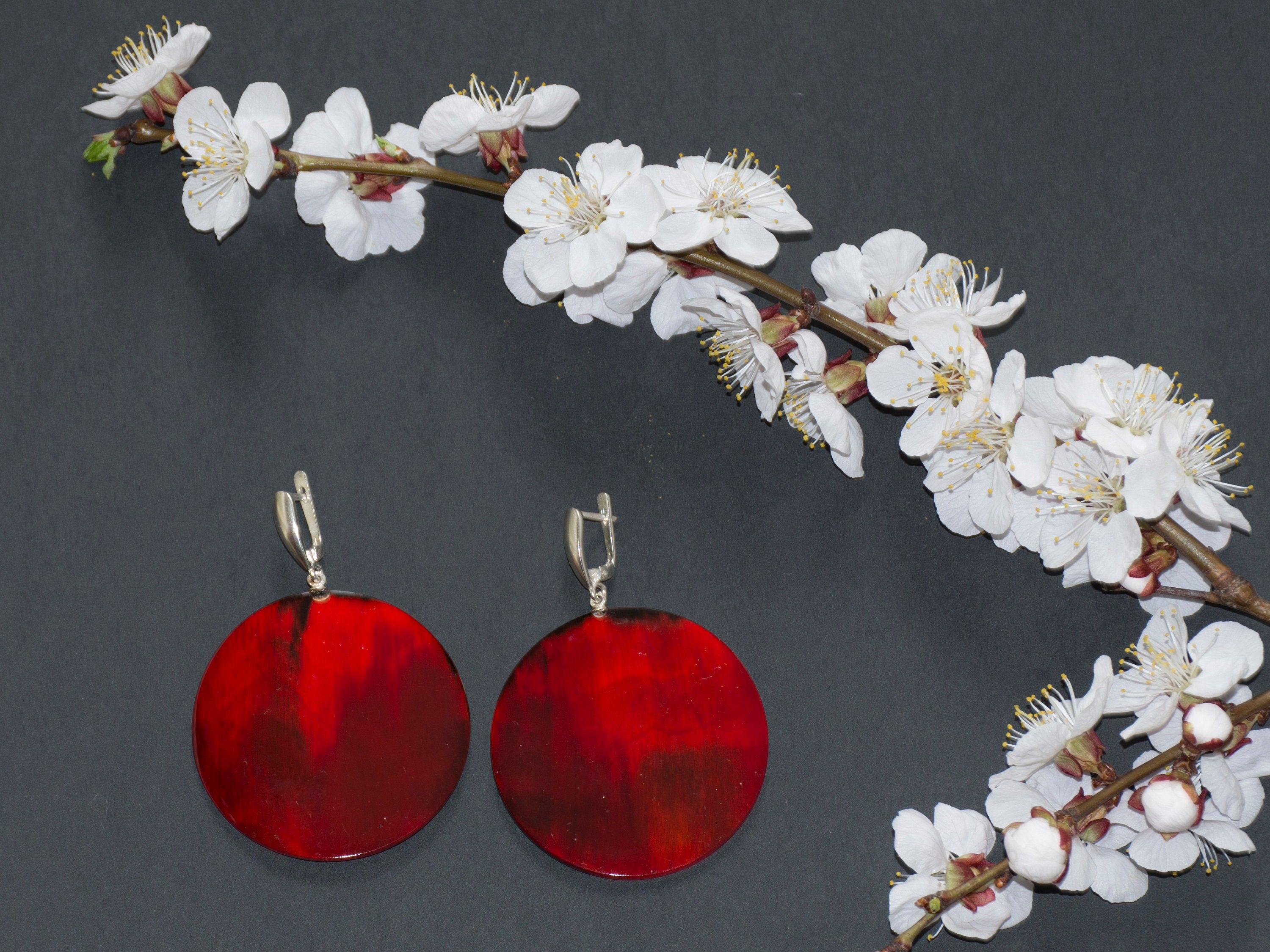 Elegant Magic Back Earrings made from buffalo horn, featuring a rich red color and silver locks, showcasing unique craftsmanship.