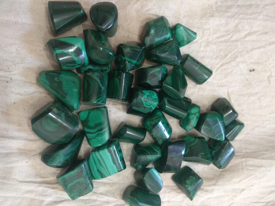 Natural green Malachite tumble stones, polished and smooth, showcasing unique patterns and colors.