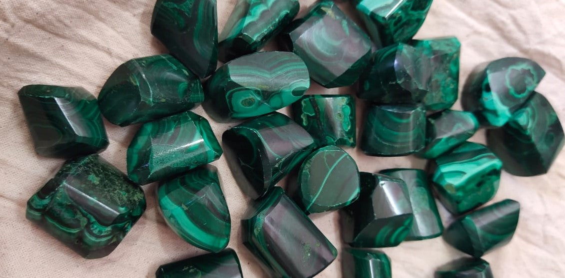 Natural green Malachite tumble stones, polished and smooth, showcasing unique patterns and colors.