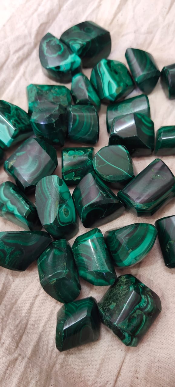 Natural green Malachite tumble stones, polished and smooth, showcasing unique patterns and colors.