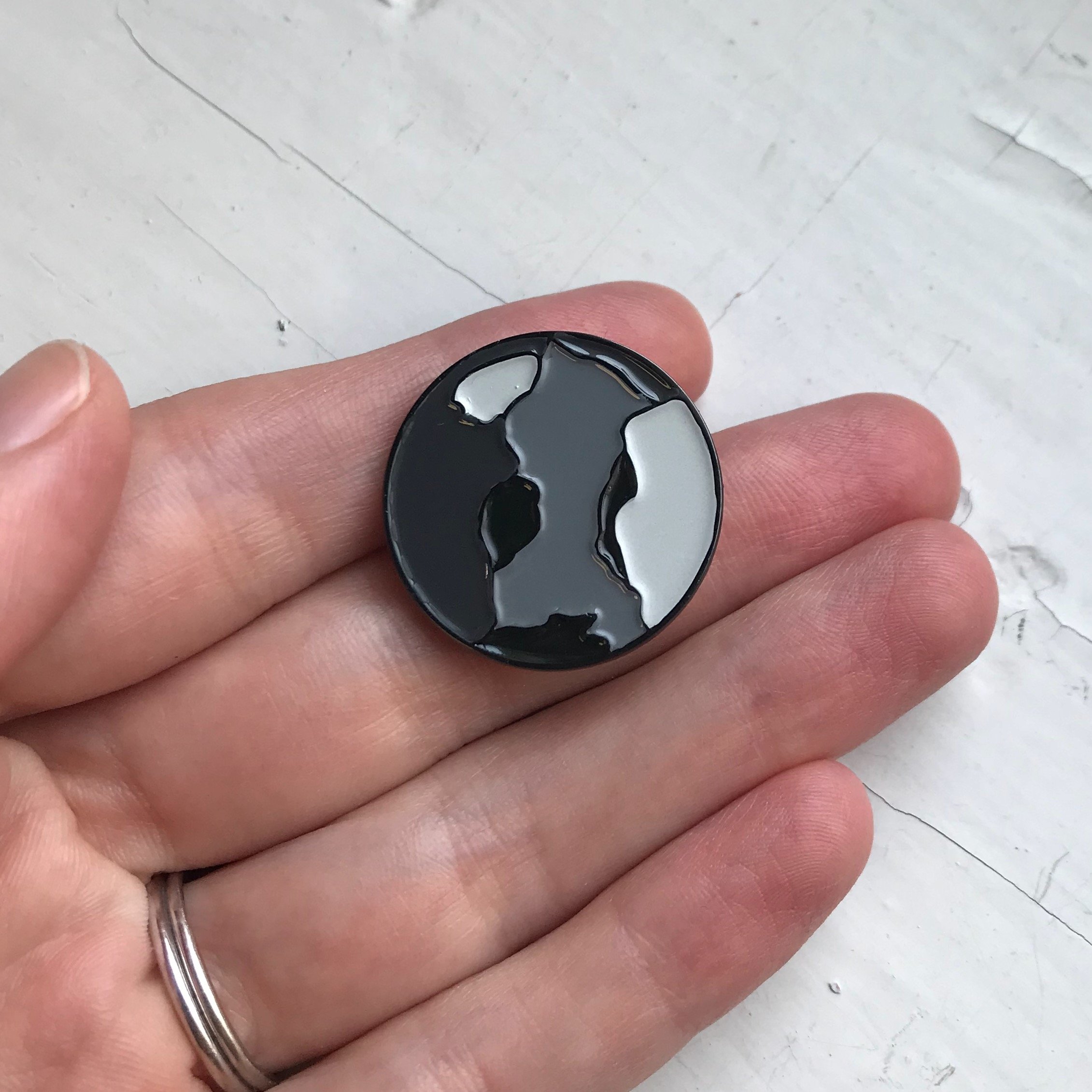 Mercury Enamel Pin featuring a gray planet design by Lauren Beacham, perfect for jackets and backpacks.