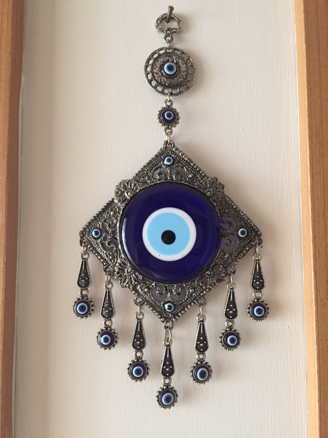 A beautifully crafted Metal Evil Eye Wall Hanging featuring a large central evil eye surrounded by seven smaller evil eyes, symbolizing protection and good luck.