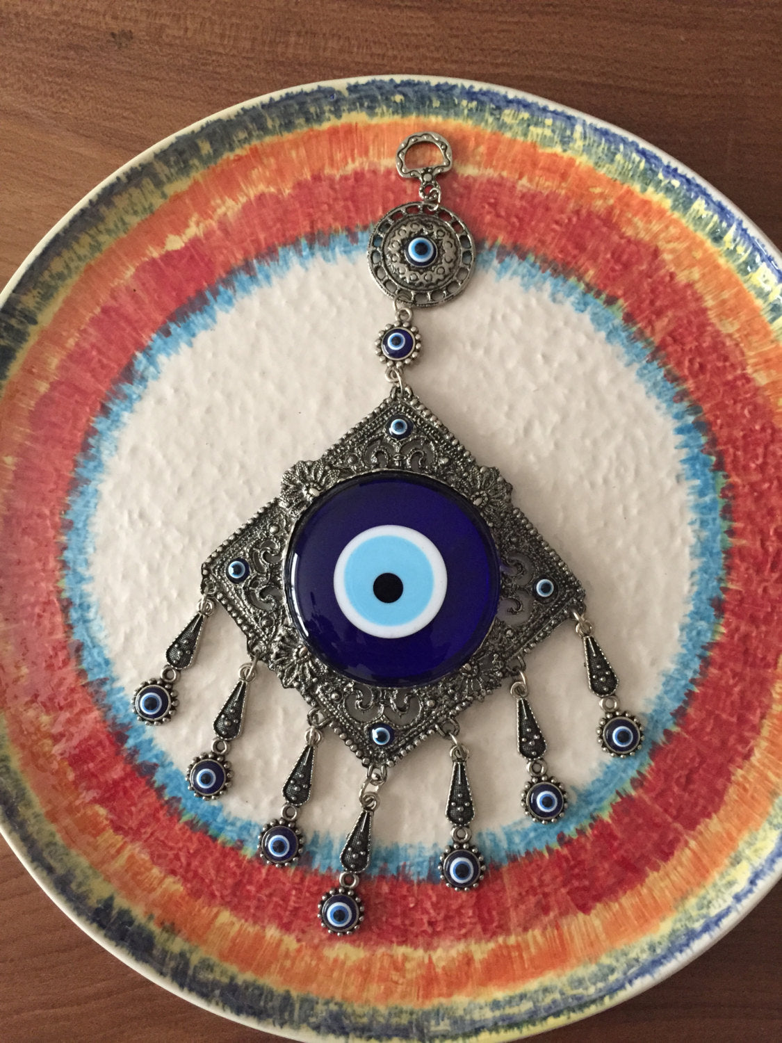 A beautifully crafted Metal Evil Eye Wall Hanging featuring a large central evil eye surrounded by seven smaller evil eyes, symbolizing protection and good luck.