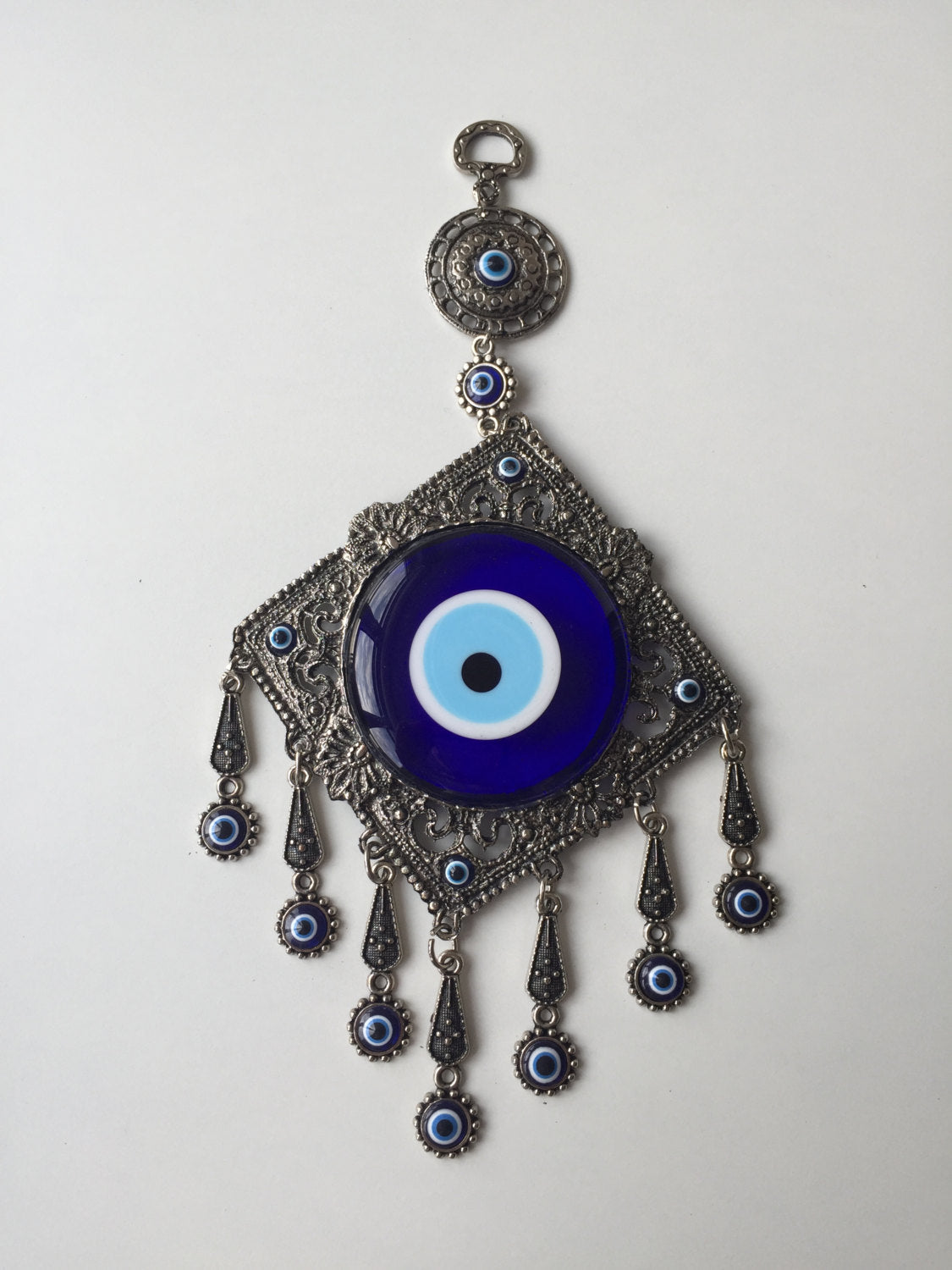 A beautifully crafted Metal Evil Eye Wall Hanging featuring a large central evil eye surrounded by seven smaller evil eyes, symbolizing protection and good luck.