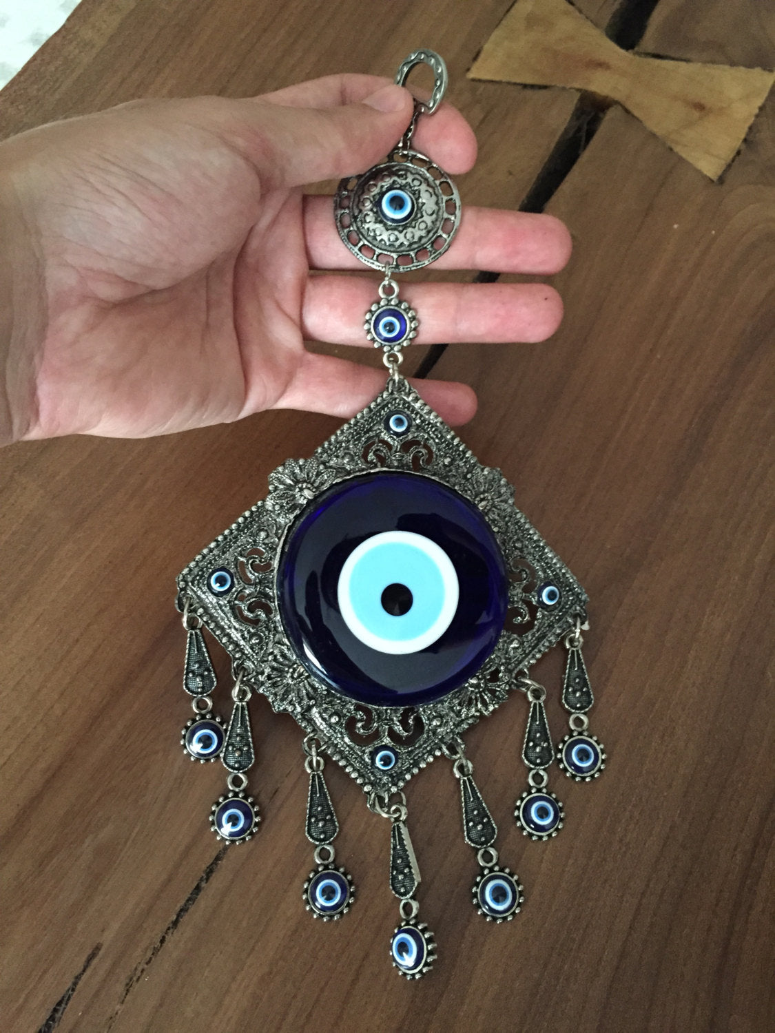 A beautifully crafted Metal Evil Eye Wall Hanging featuring a large central evil eye surrounded by seven smaller evil eyes, symbolizing protection and good luck.