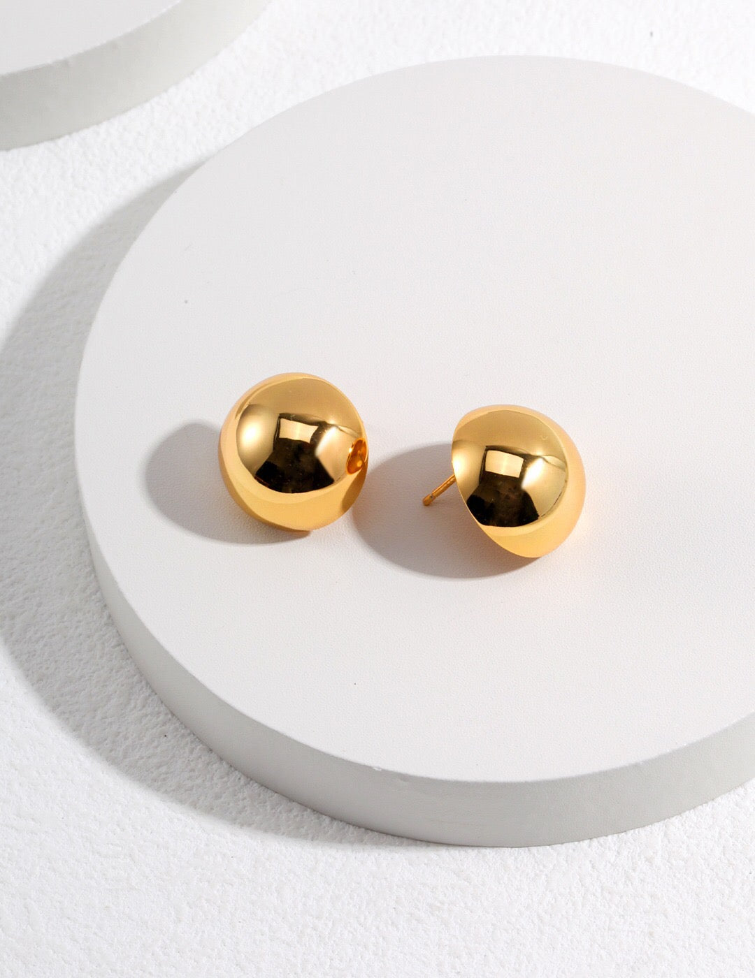 A pair of elegant Metal Half Ball Stud Earrings made from sterling silver with a gold vermeil finish, showcasing their shiny surface and round shape.