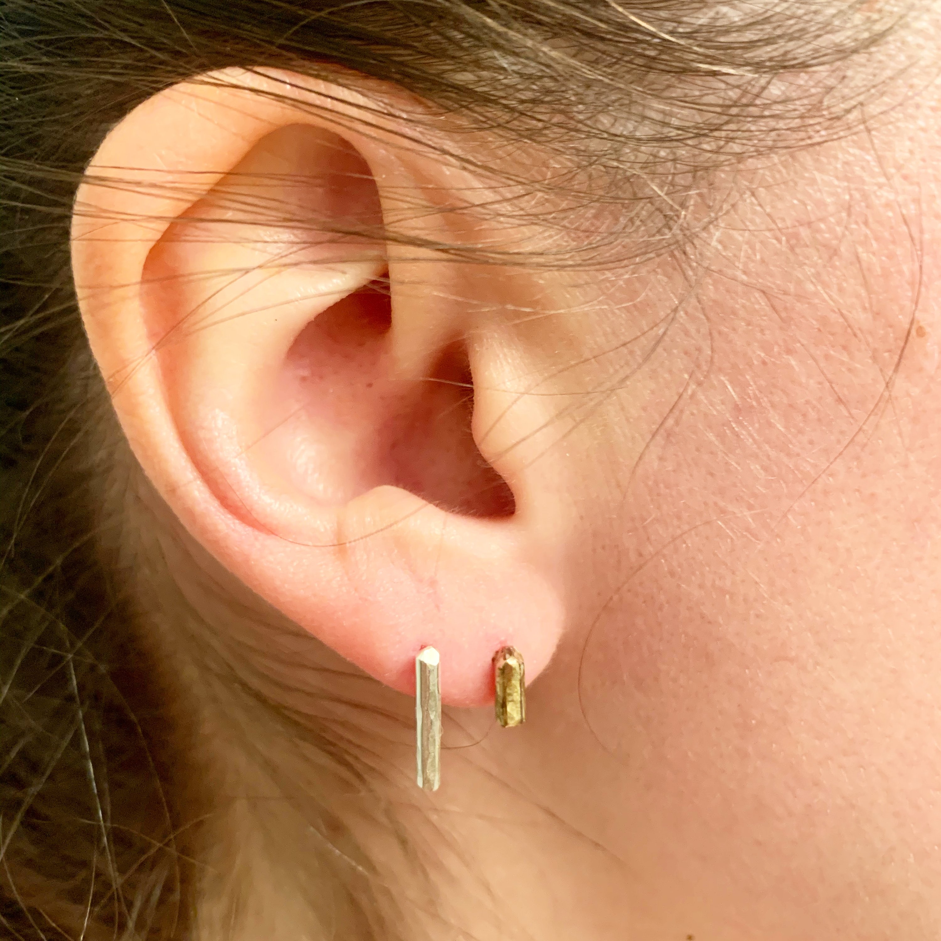 A pair of Mini Balance Stud Earrings - 1/4" featuring tiny hammered rods in copper, sterling silver, and yellow gold fill options, showcasing their minimalist design.