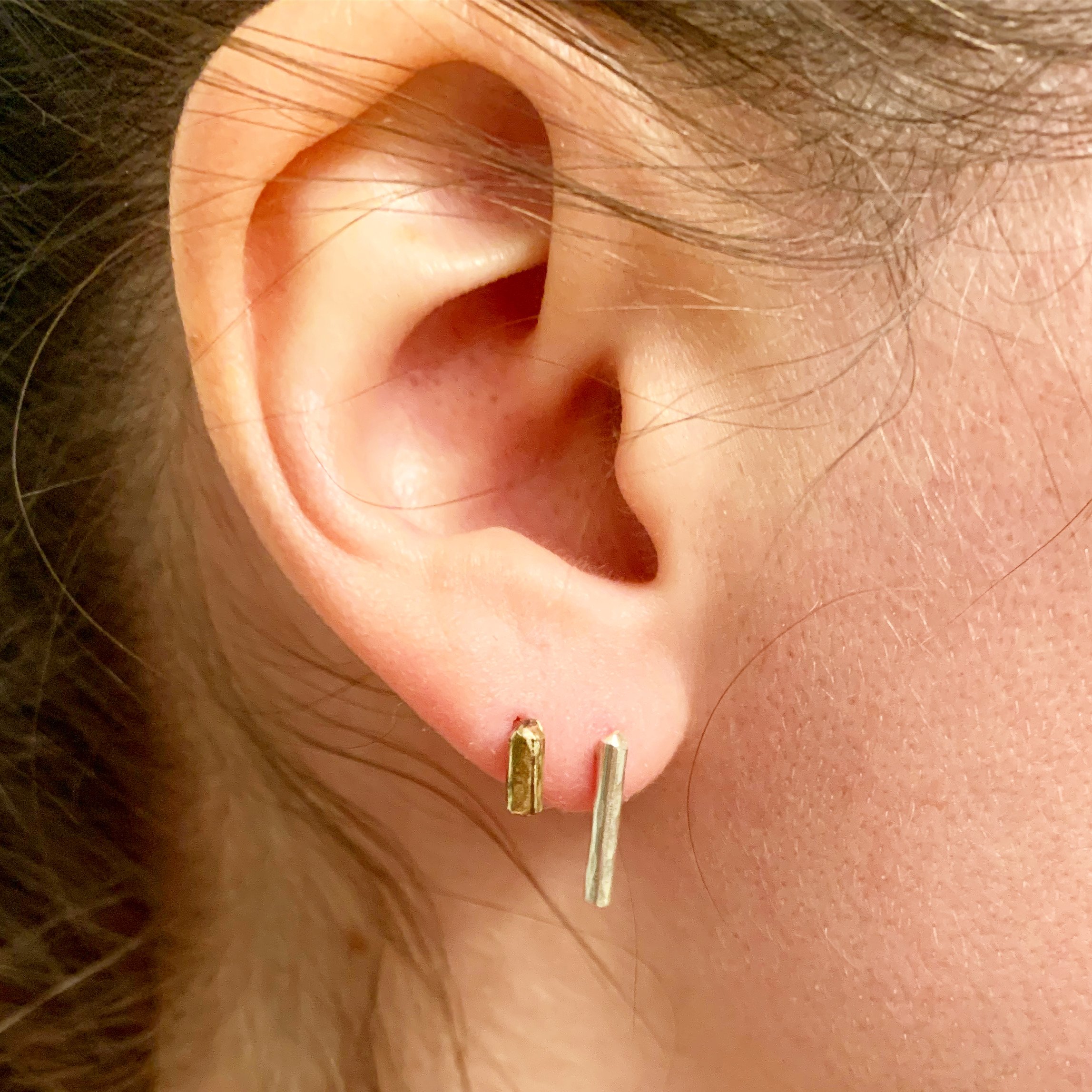 A pair of Mini Balance Stud Earrings - 1/4" featuring tiny hammered rods in copper, sterling silver, and yellow gold fill options, showcasing their minimalist design.