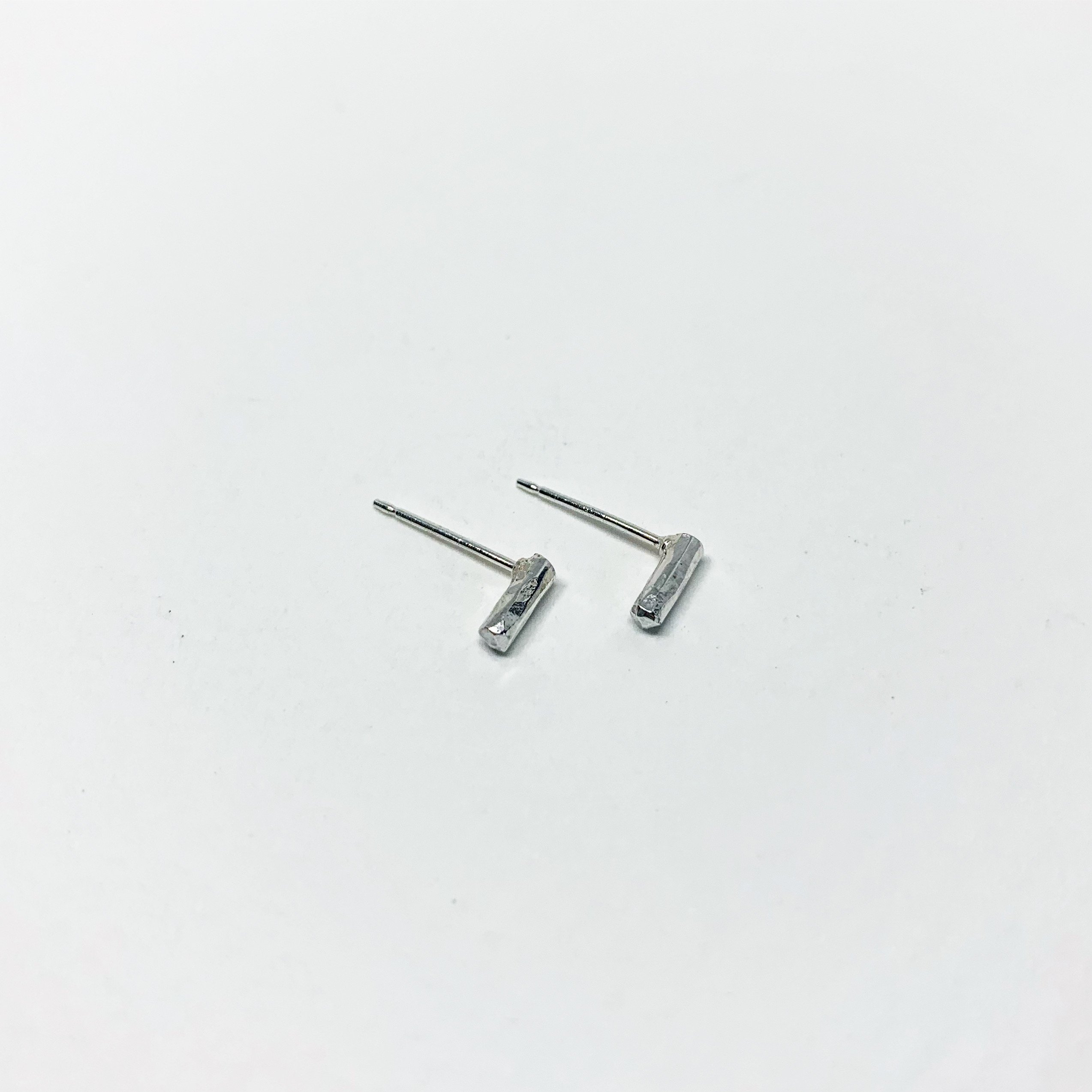 A pair of Mini Balance Stud Earrings - 1/4" featuring tiny hammered rods in copper, sterling silver, and yellow gold fill options, showcasing their minimalist design.