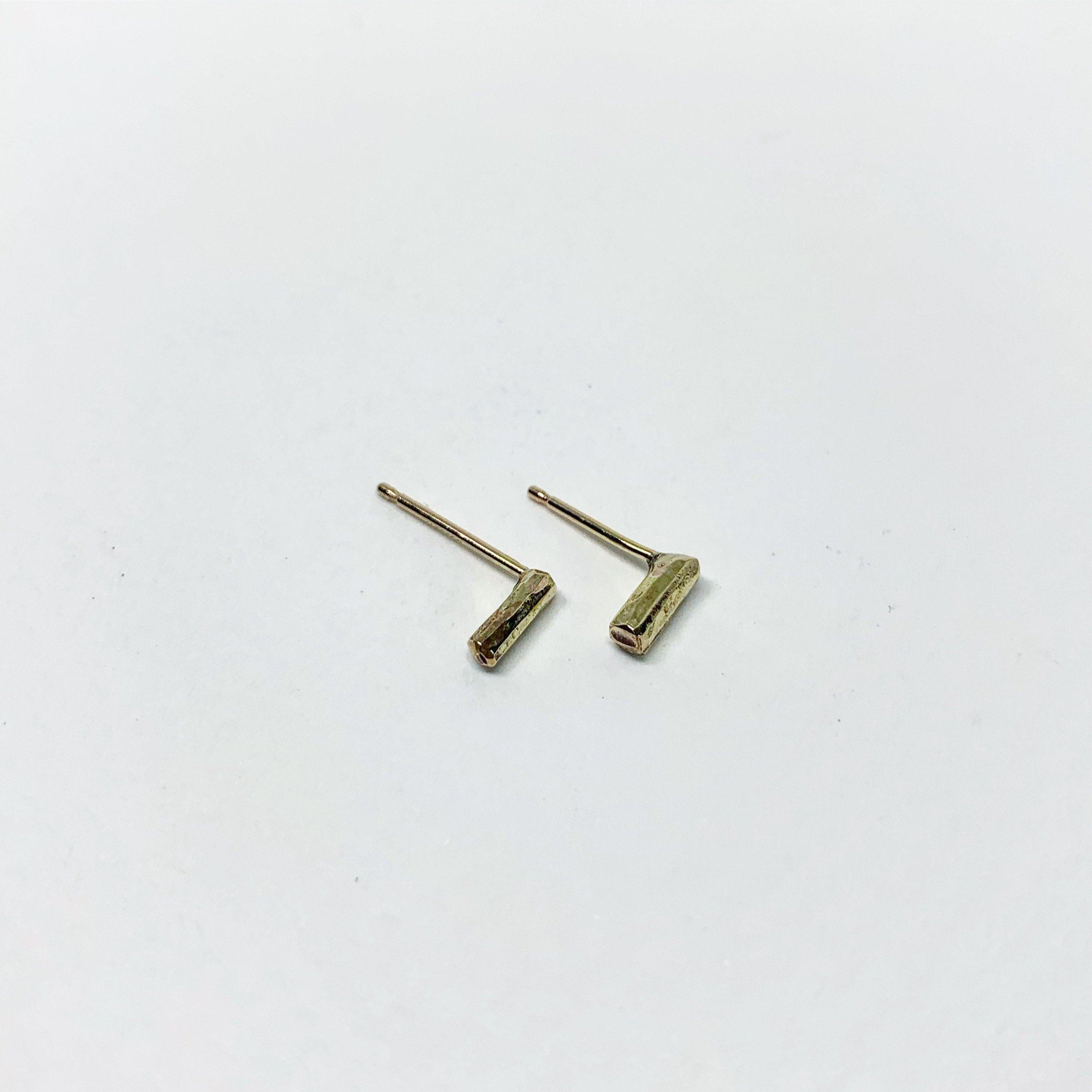 A pair of Mini Balance Stud Earrings - 1/4" featuring tiny hammered rods in copper, sterling silver, and yellow gold fill options, showcasing their minimalist design.