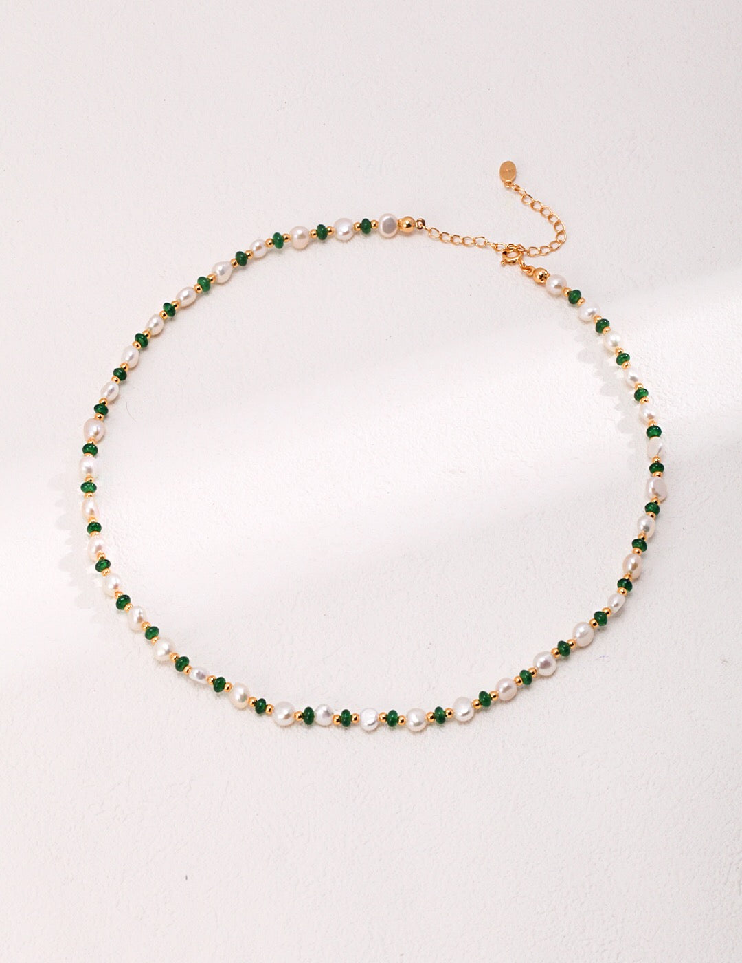 A delicate Mini Emerald Freshwater Pearl Necklace featuring sterling silver and gold vermeil, adorned with emerald stones and irregular freshwater pearls.