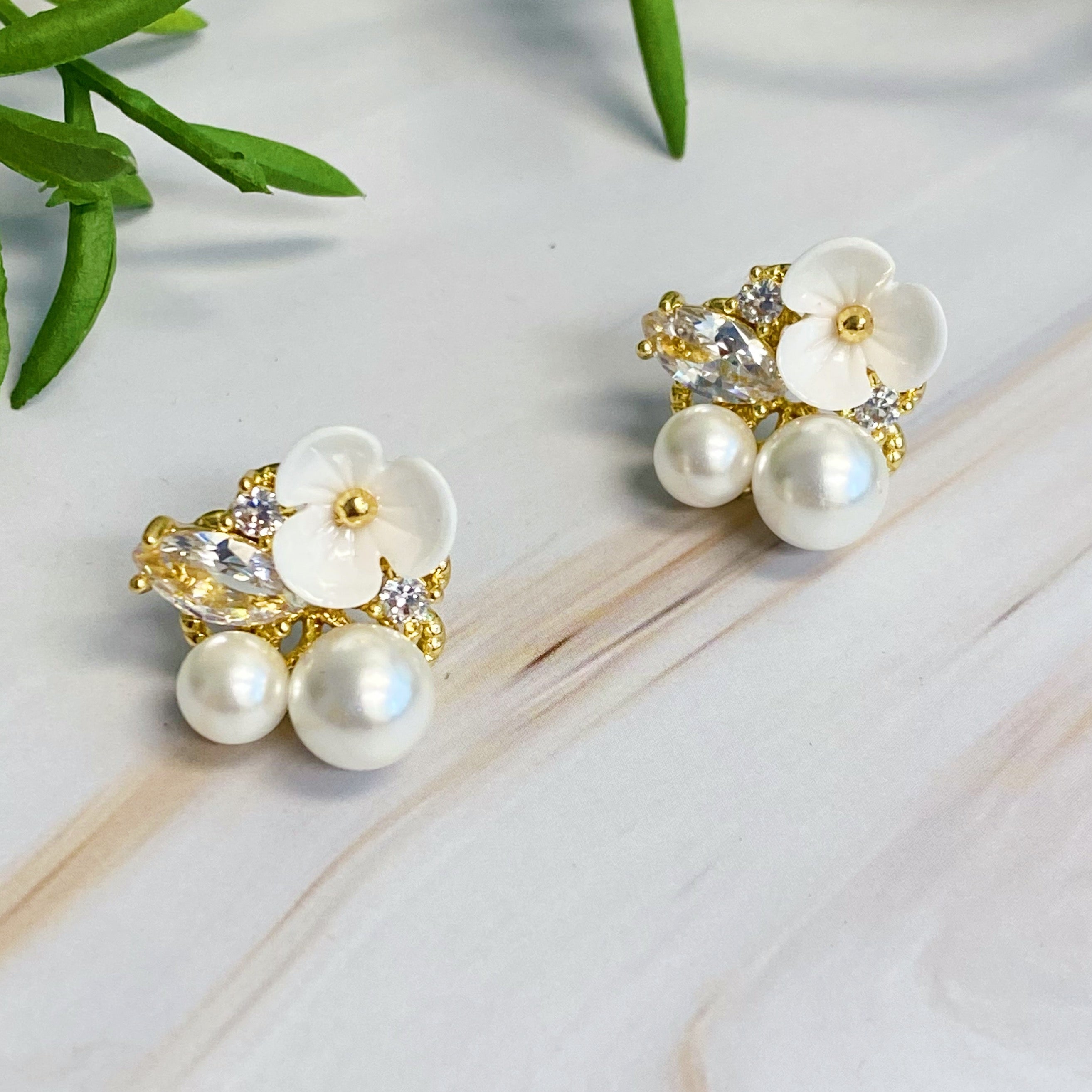 Mini Flower Jeweled Stud Earrings featuring sparkling cubic zirconia and delicate pearl accents on a gold plated brass base.