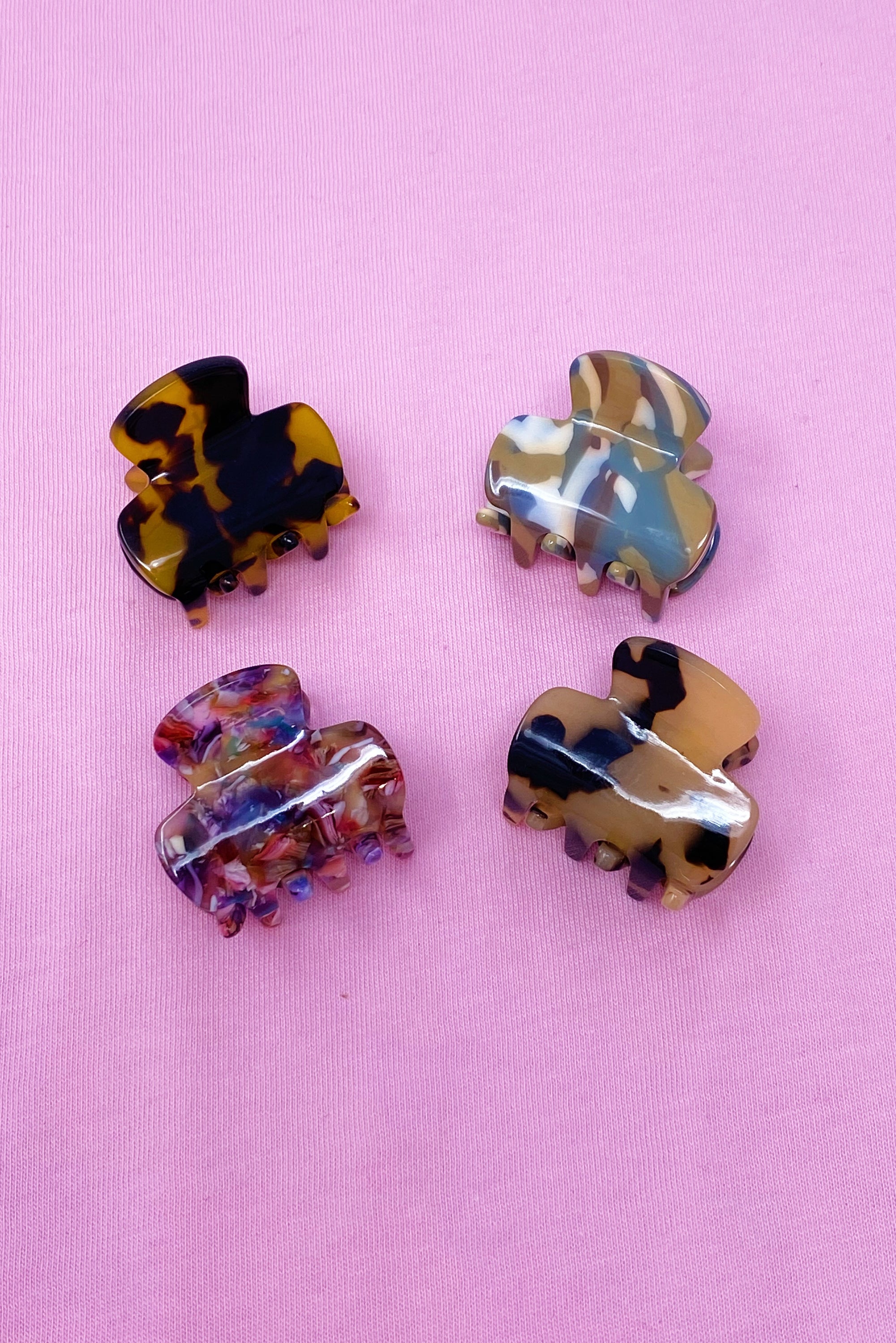 Mini acrylic hair claw clip in various tortoise designs, perfect for securing half-up hairstyles.