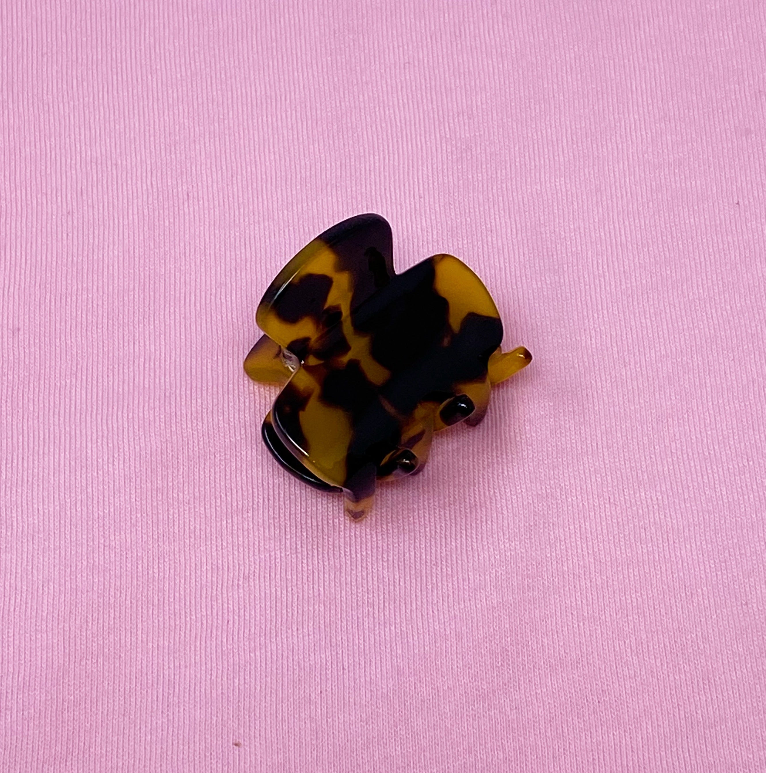 Mini acrylic hair claw clip in various tortoise designs, perfect for securing half-up hairstyles.