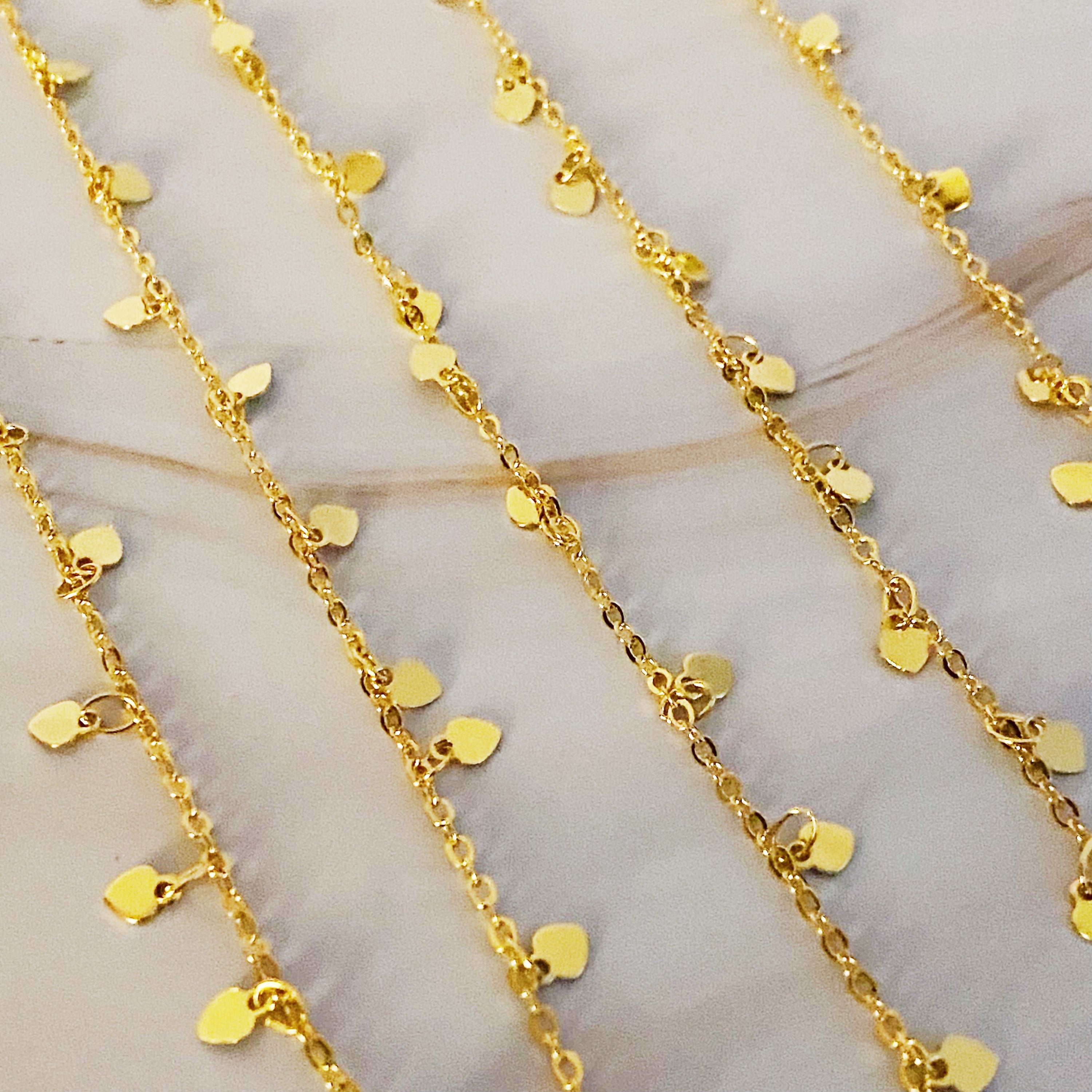 A long necklace featuring mini hearts on a gold chain, showcasing its elegant design and versatility.